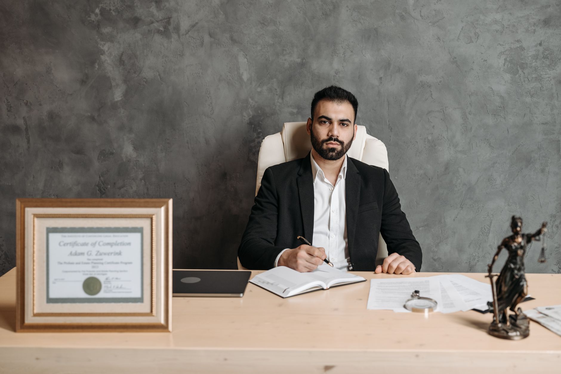 Confident man sitting at a desk surrounded by legal documents and a certificate.