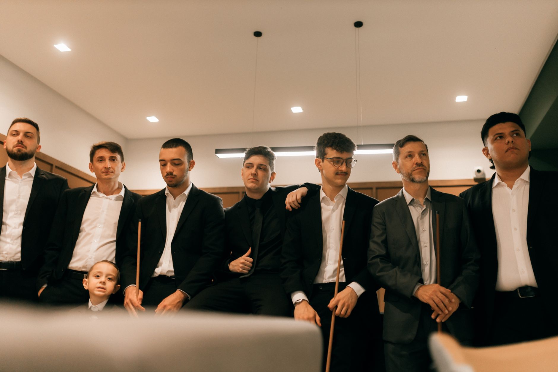 Group of businessmen in formal attire posing indoors, suggesting a corporate or professional environment.