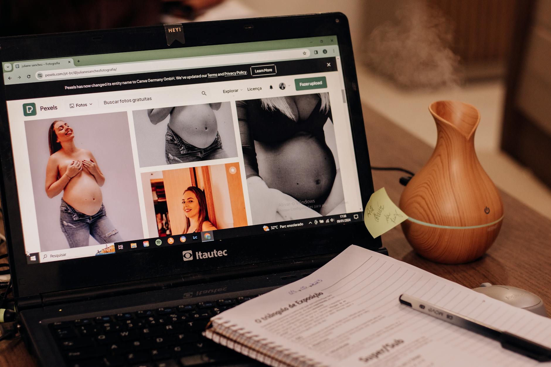 A laptop displays pregnancy images online beside a notepad and vase on a desk, emphasizing health and lifestyle.