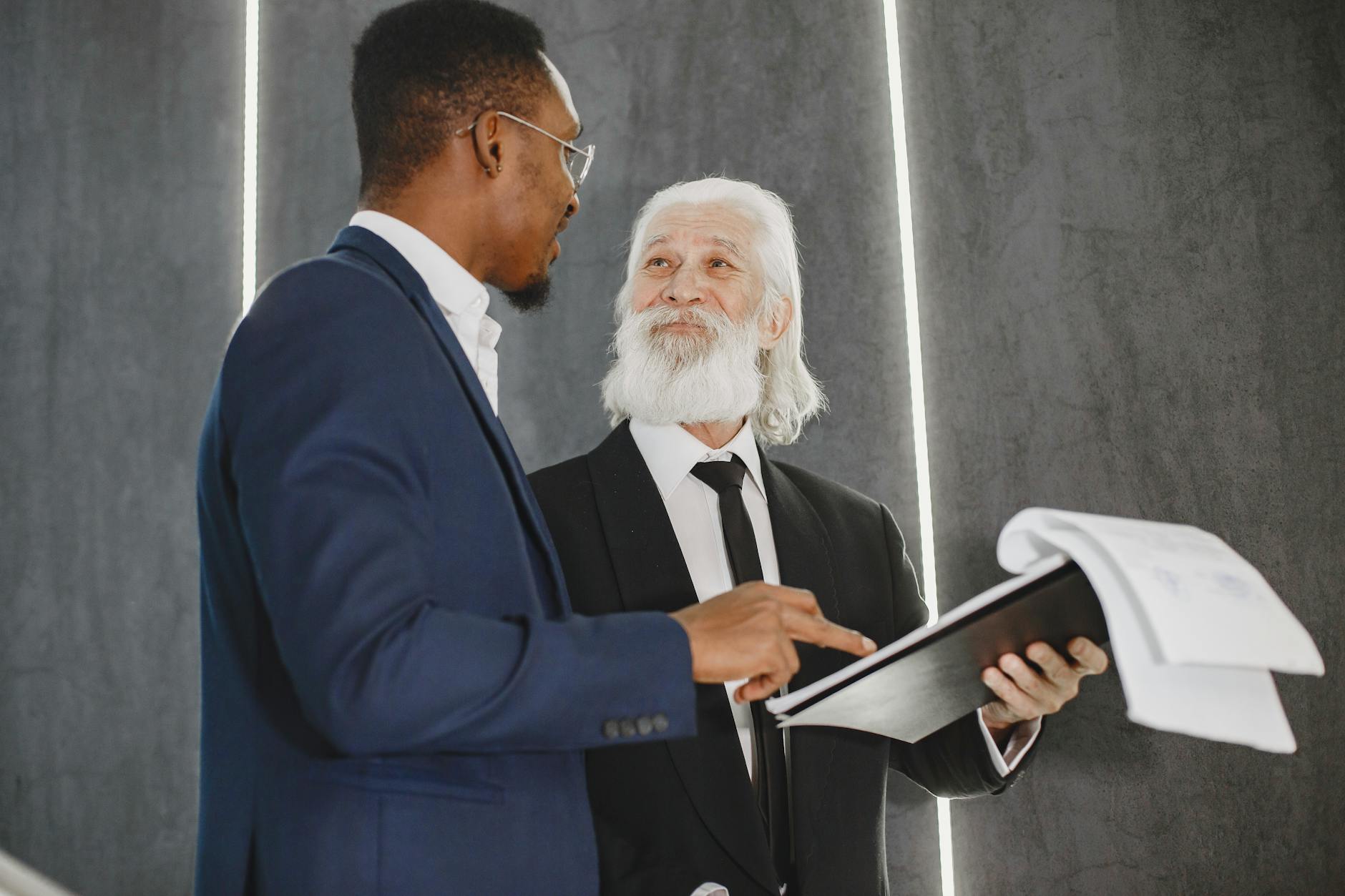 Two businessmen discussing documents in a modern office setting, highlighting professional diversity.