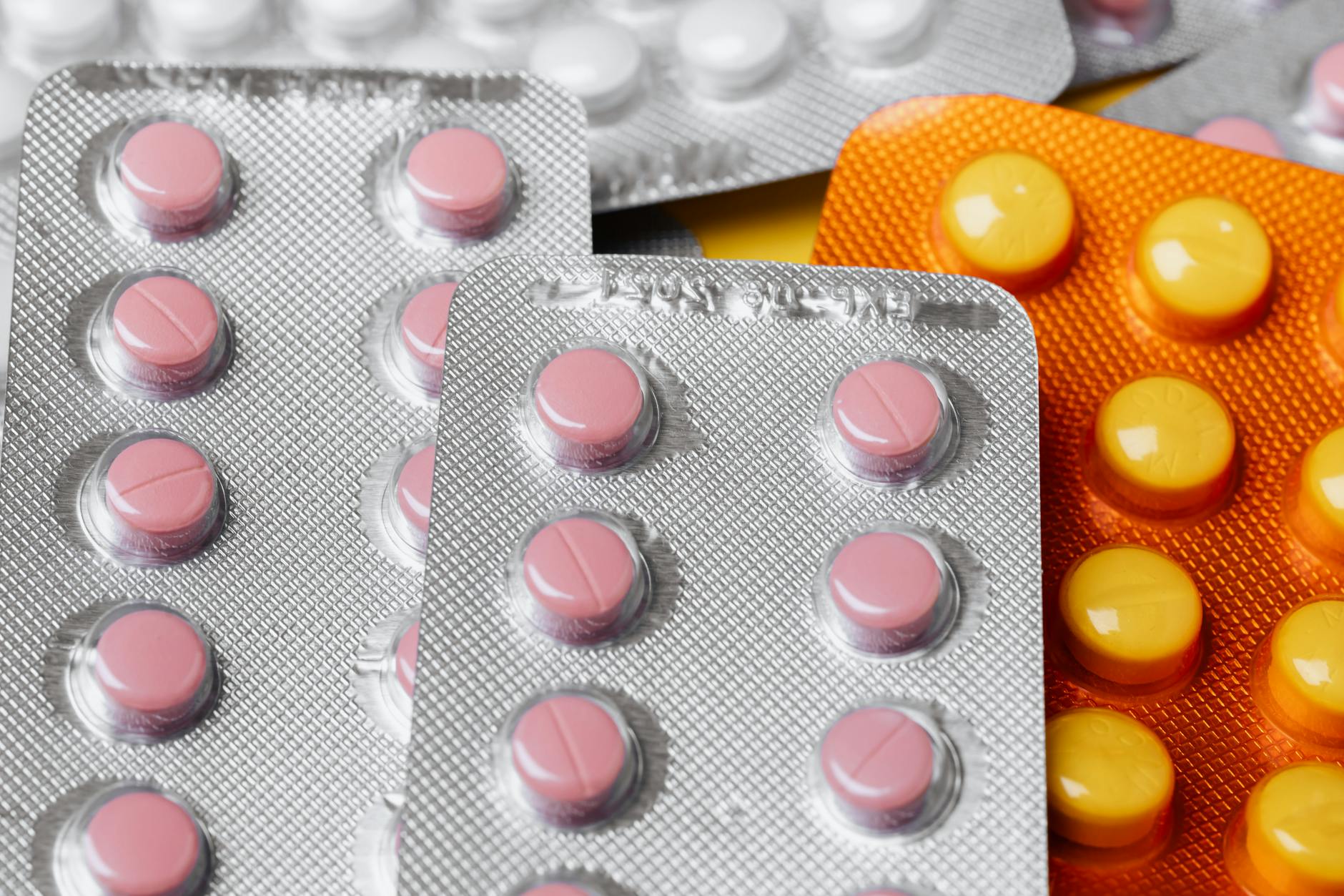 From above closeup of various multicolored pills of different sizes in plastic blister packs placed together under bright light