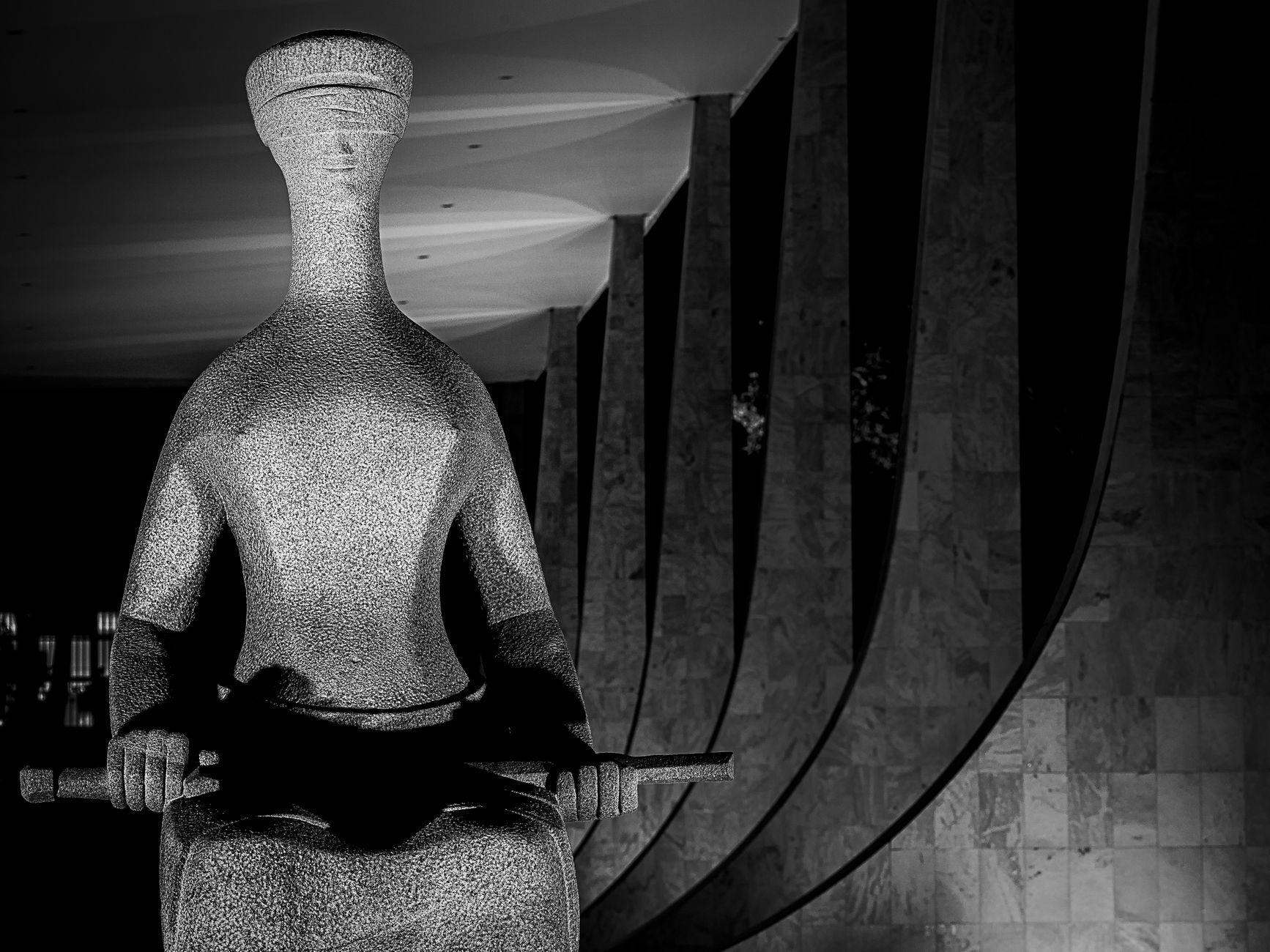 Black and white photo of a modern sculpture with architectural backdrop.