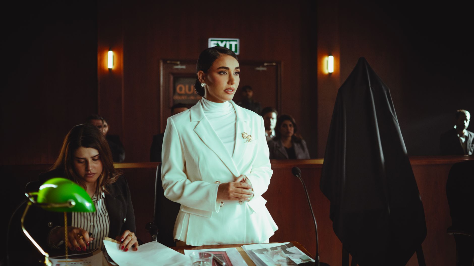 Confident professional woman stands in a courtroom, representing legal authority.
