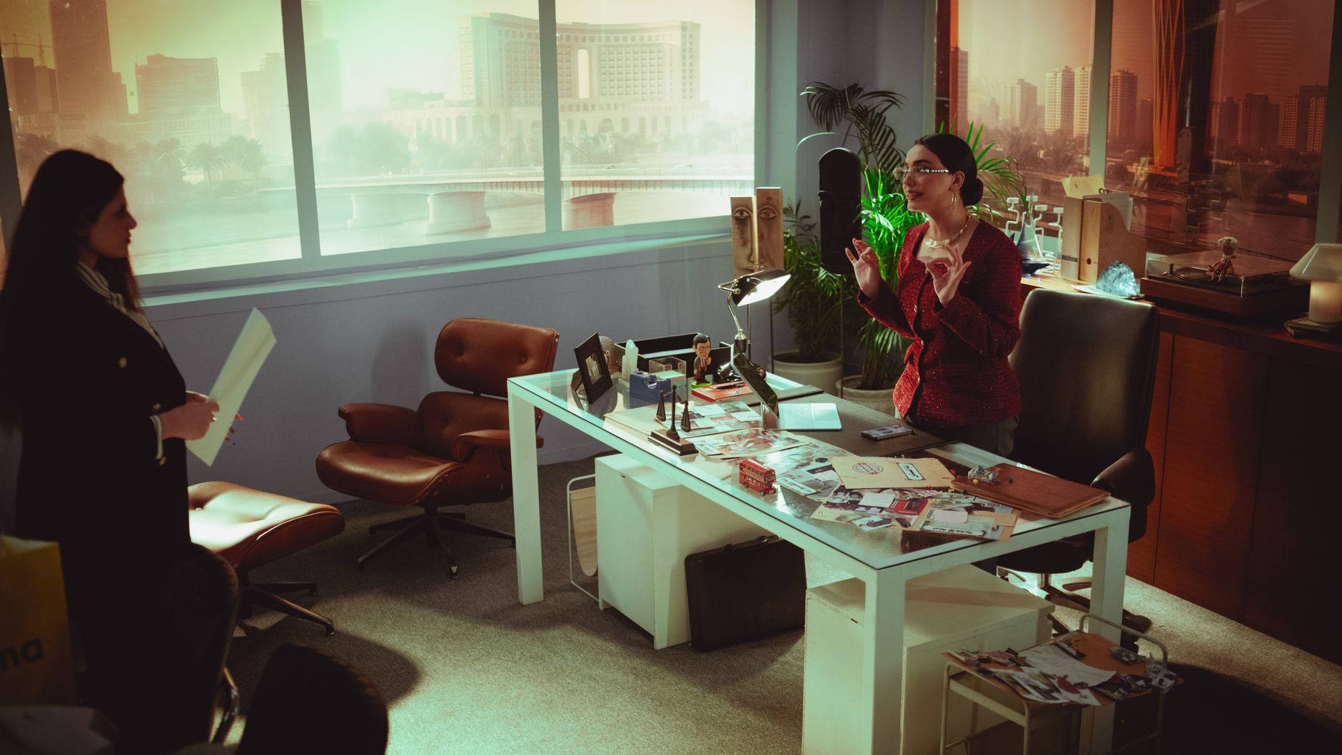 Two professional women engage in a business meeting in a modern Baghdad office with a view.