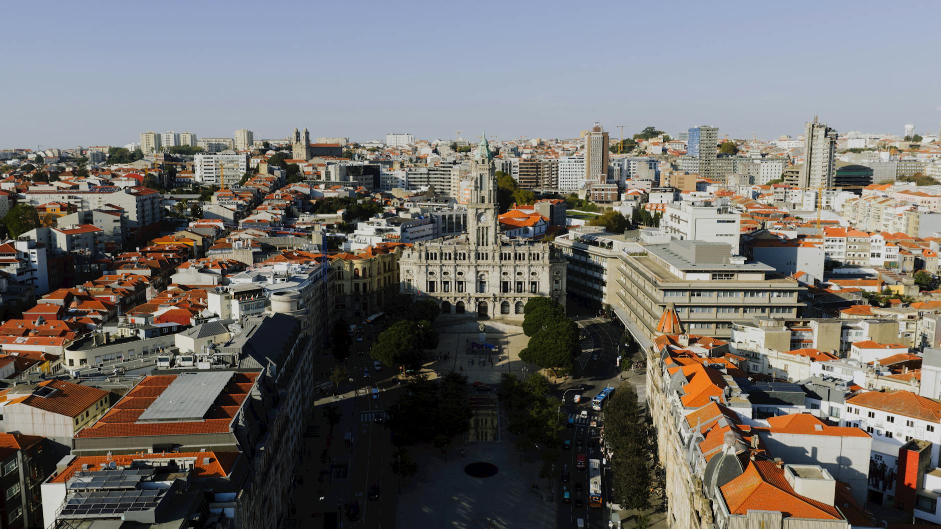 Aerial view of Porto's vibrant cityscape featuring the iconic Porto City Hall with red-tiled rooftops under a clear sky.