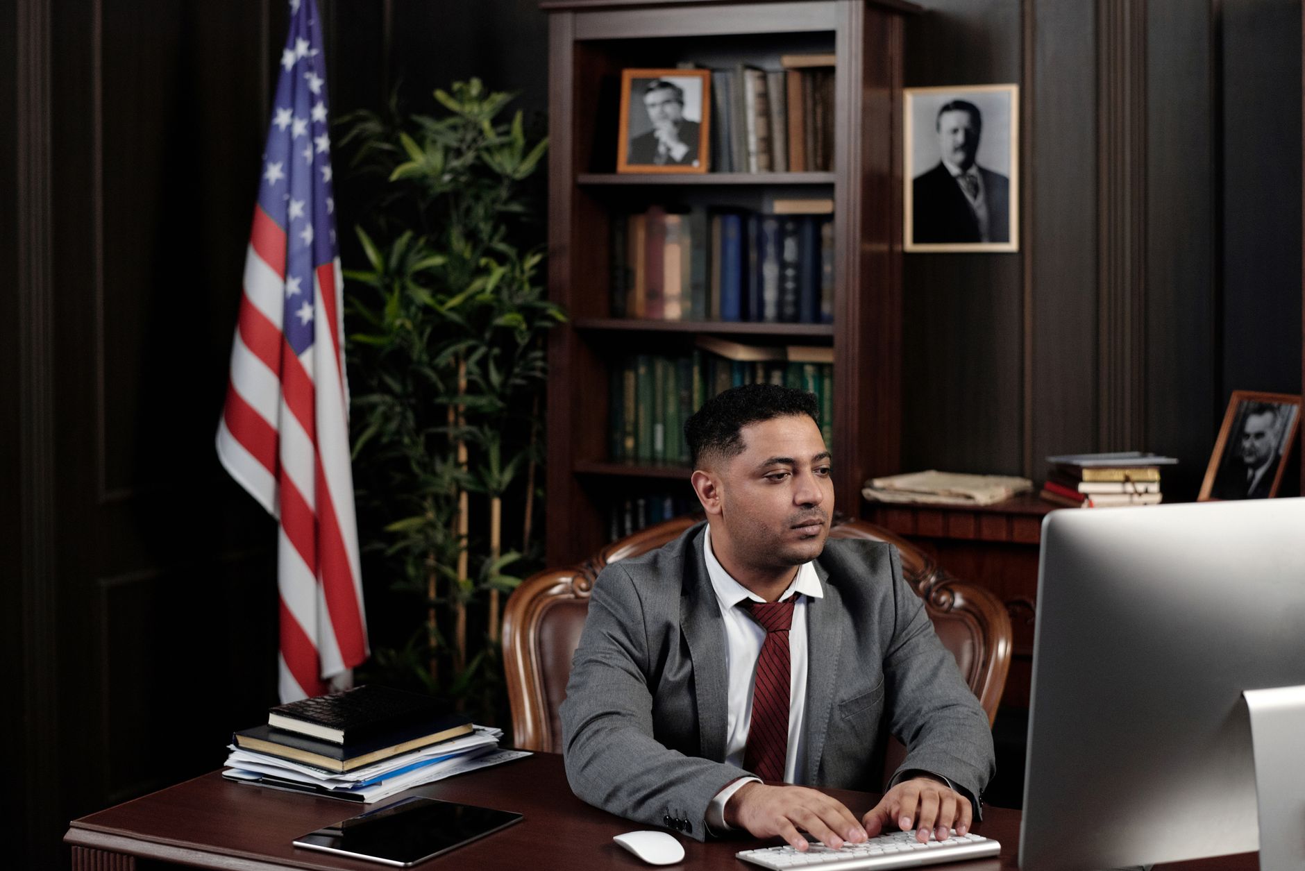 A confident businessman works at his desk with an American flag in his office.