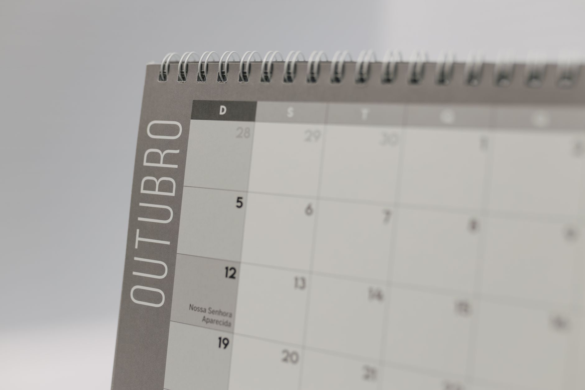 A close-up view of a desktop calendar displaying the month of October with spiral binding.