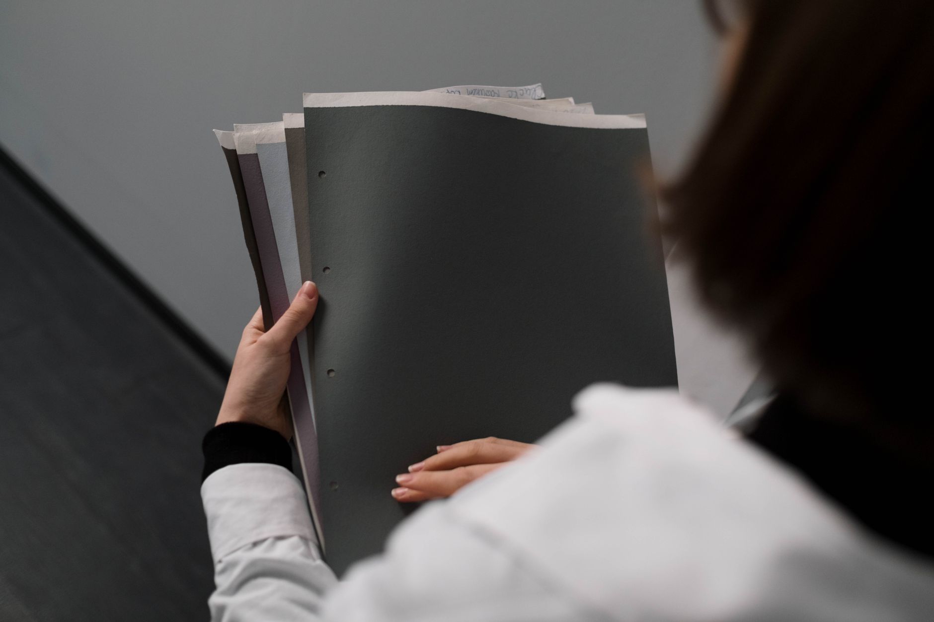 Close-up of a businesswoman holding and reviewing documents in an office setting.