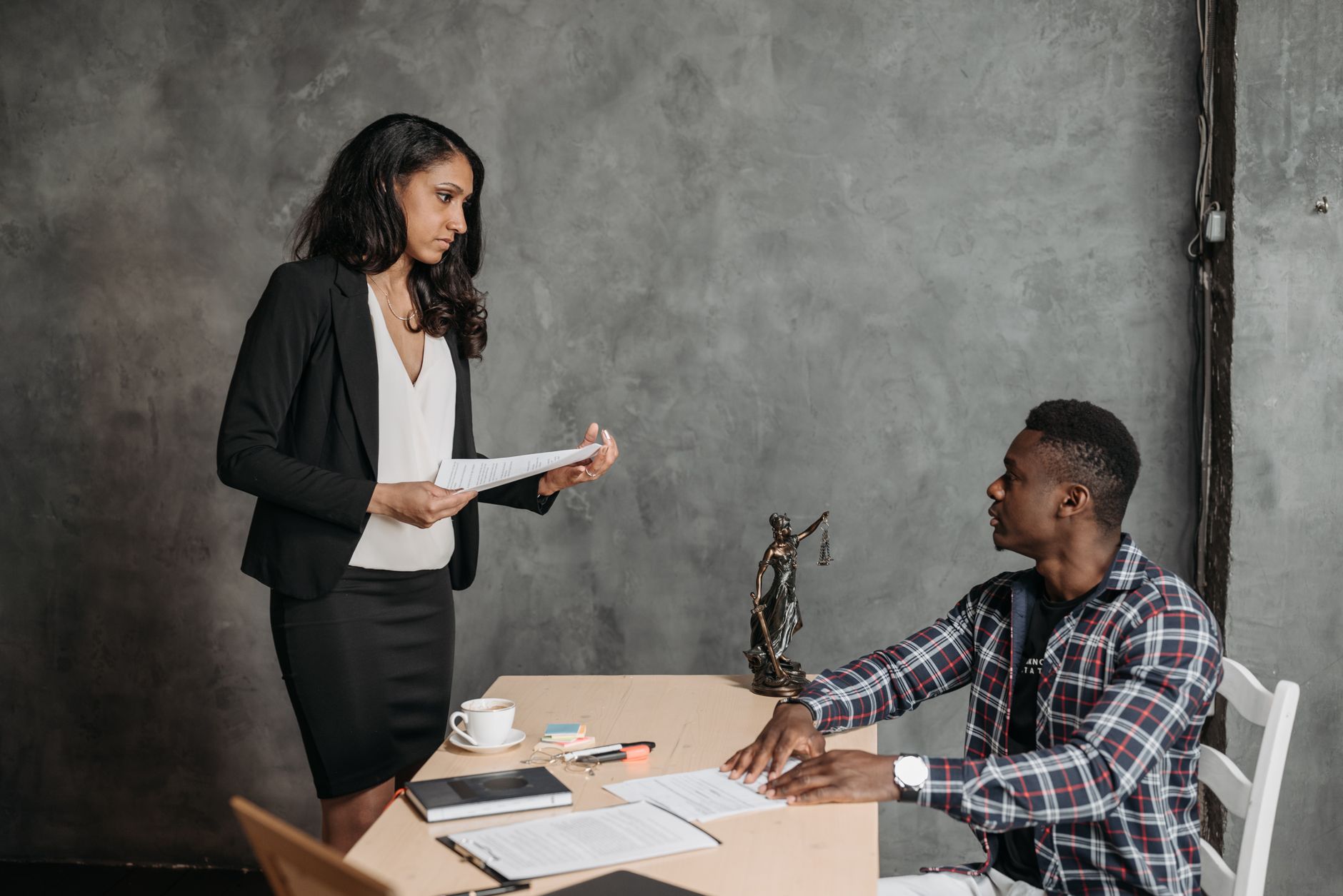 A formal office meeting between a woman and a man discussing documents.