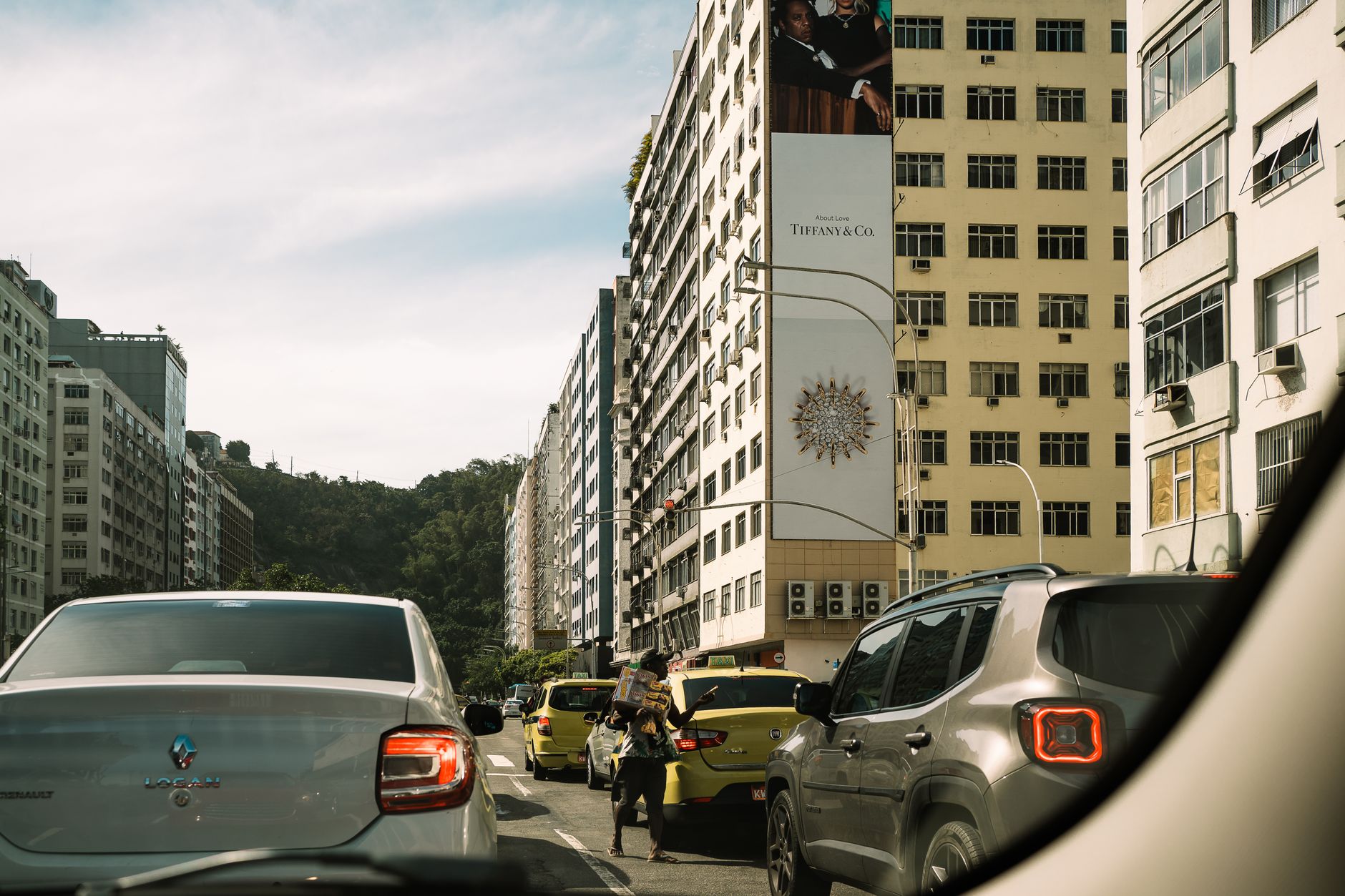 Busy city street in Rio de Janeiro featuring cars and tall buildings under a clear sky.