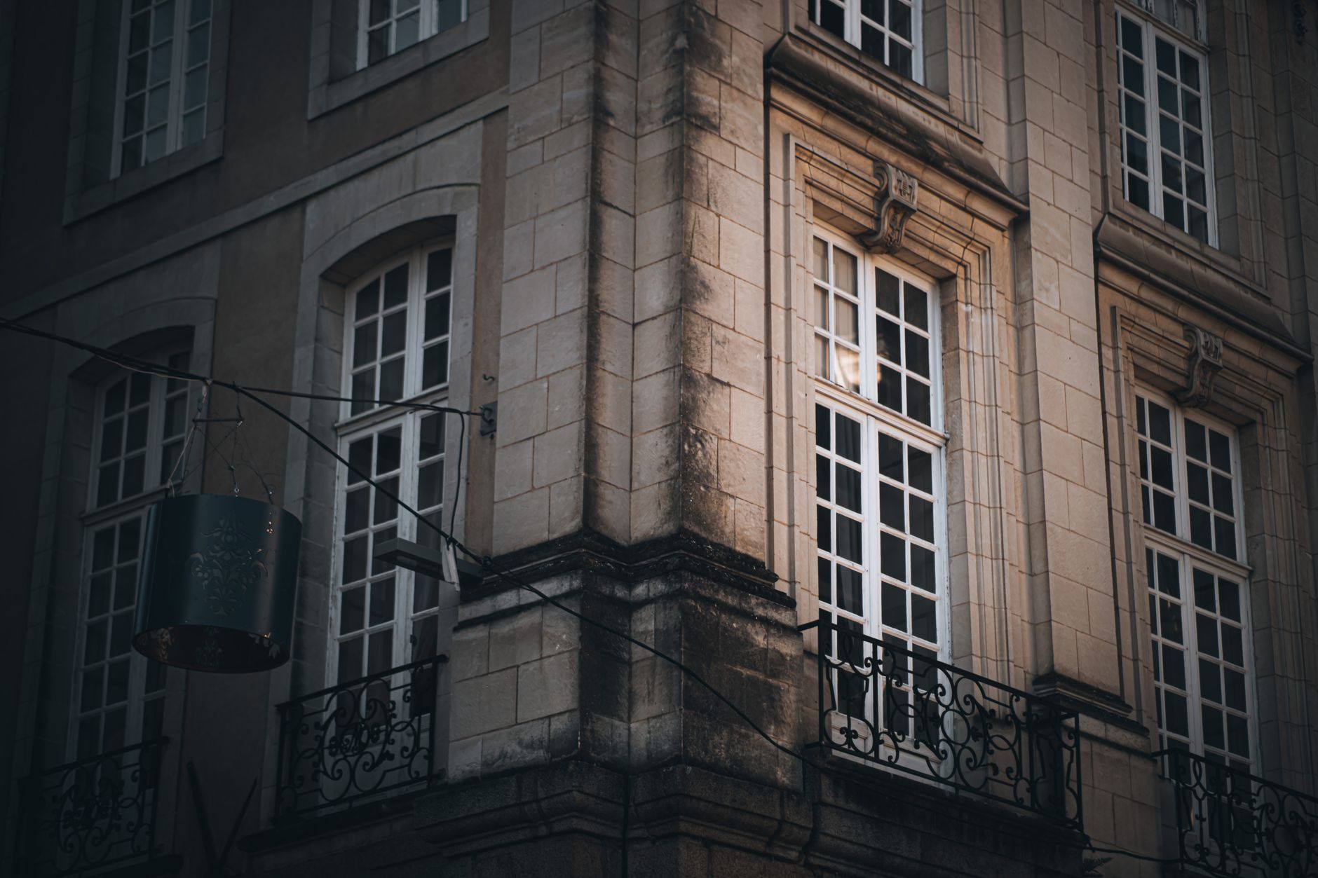 Close-up of a historic building corner with classic architectural elements and iron balcony.