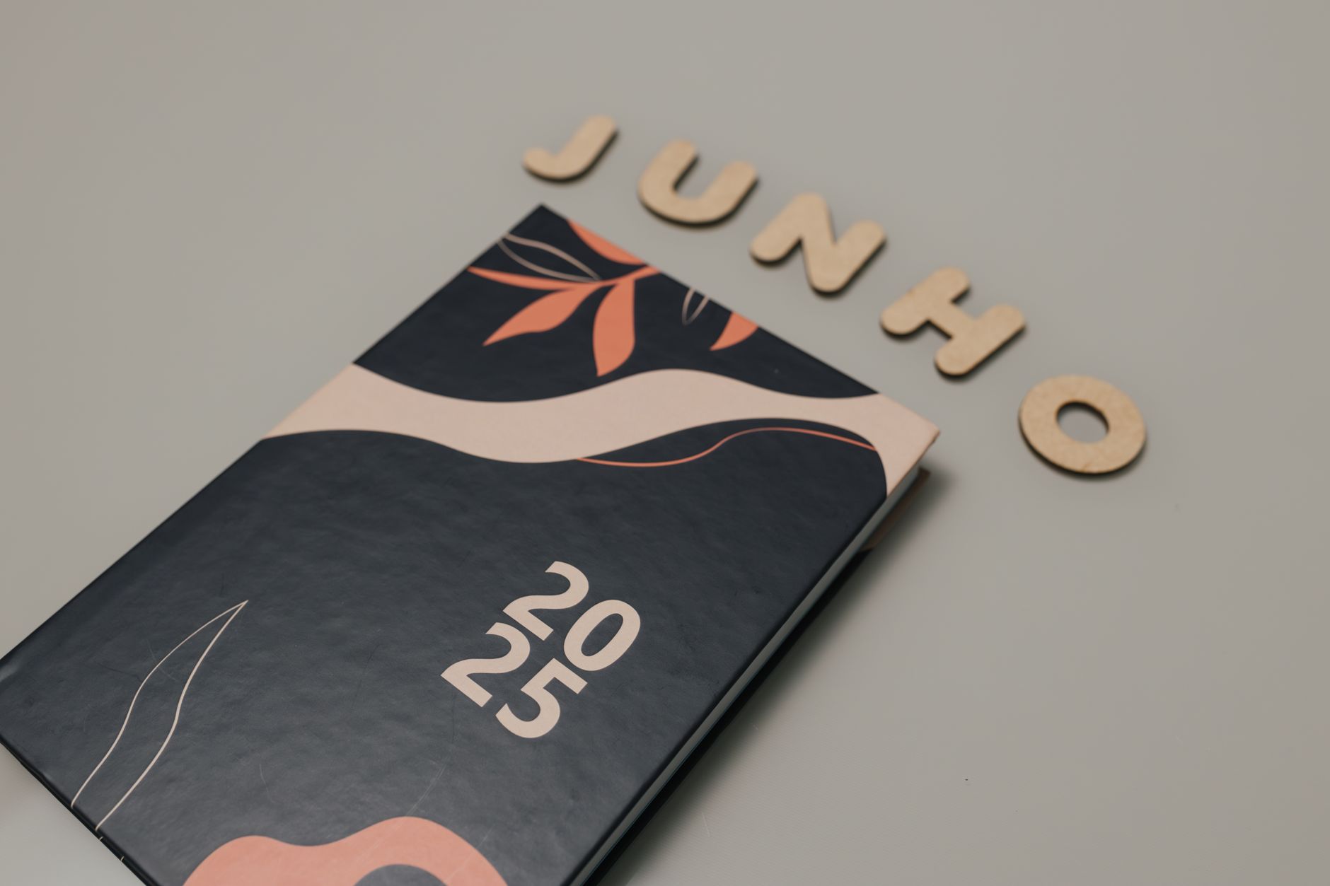 A sleek 2025 planner with a modern design sits beneath cutout letters spelling 'Junho'. Perfect for organizing and planning.