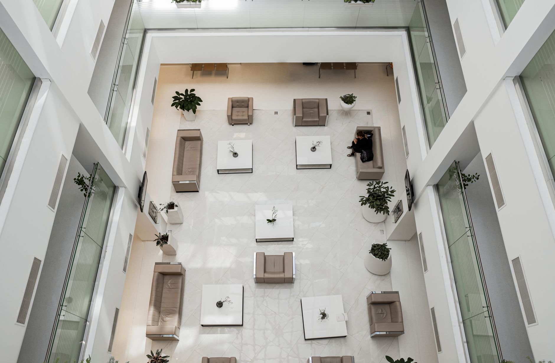 Aerial view of a contemporary lobby in Baku featuring stylish sofas, tables, and potted plants.