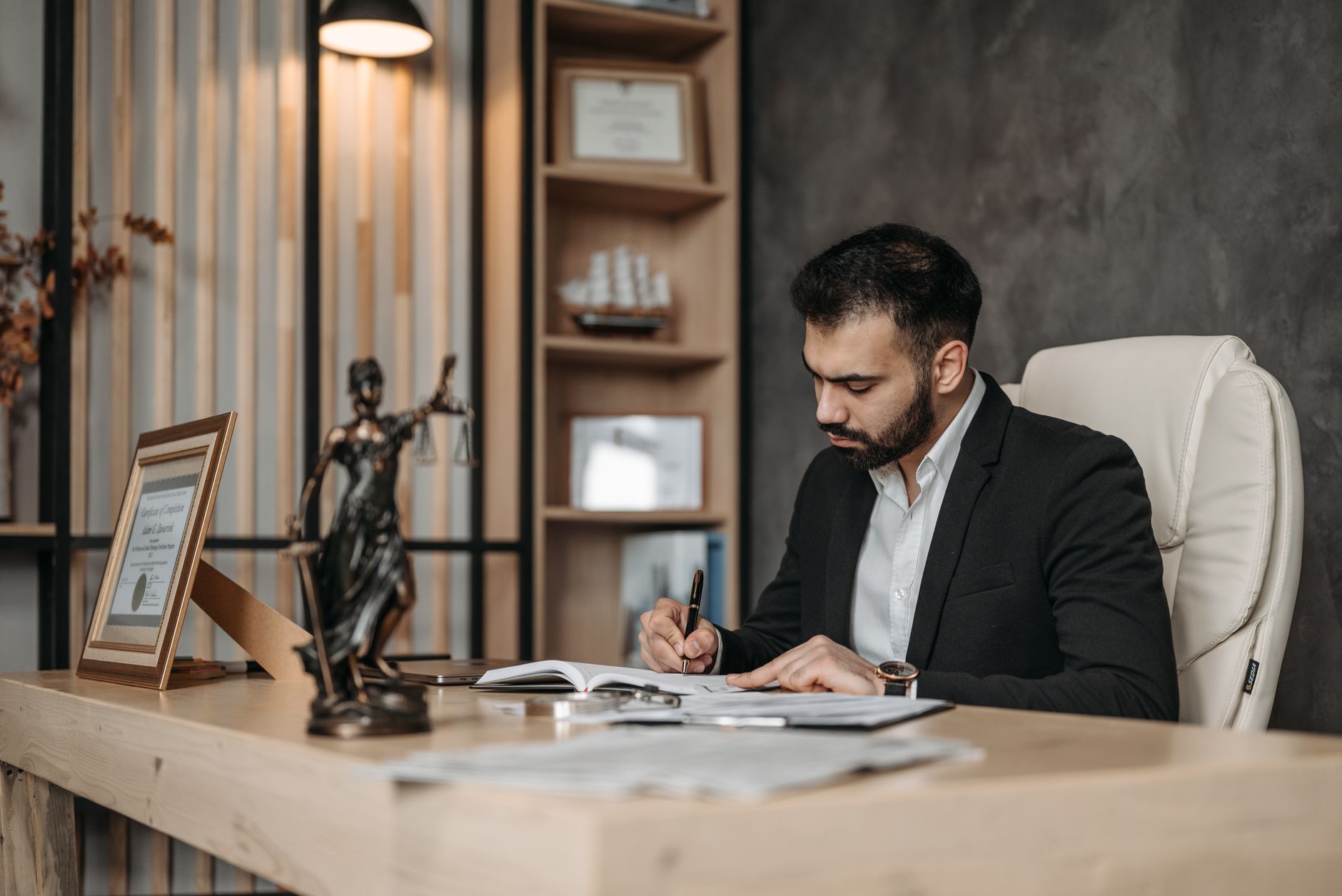 A focused lawyer in an office setting writing and reviewing legal documents, symbolizing expertise and professionalism.