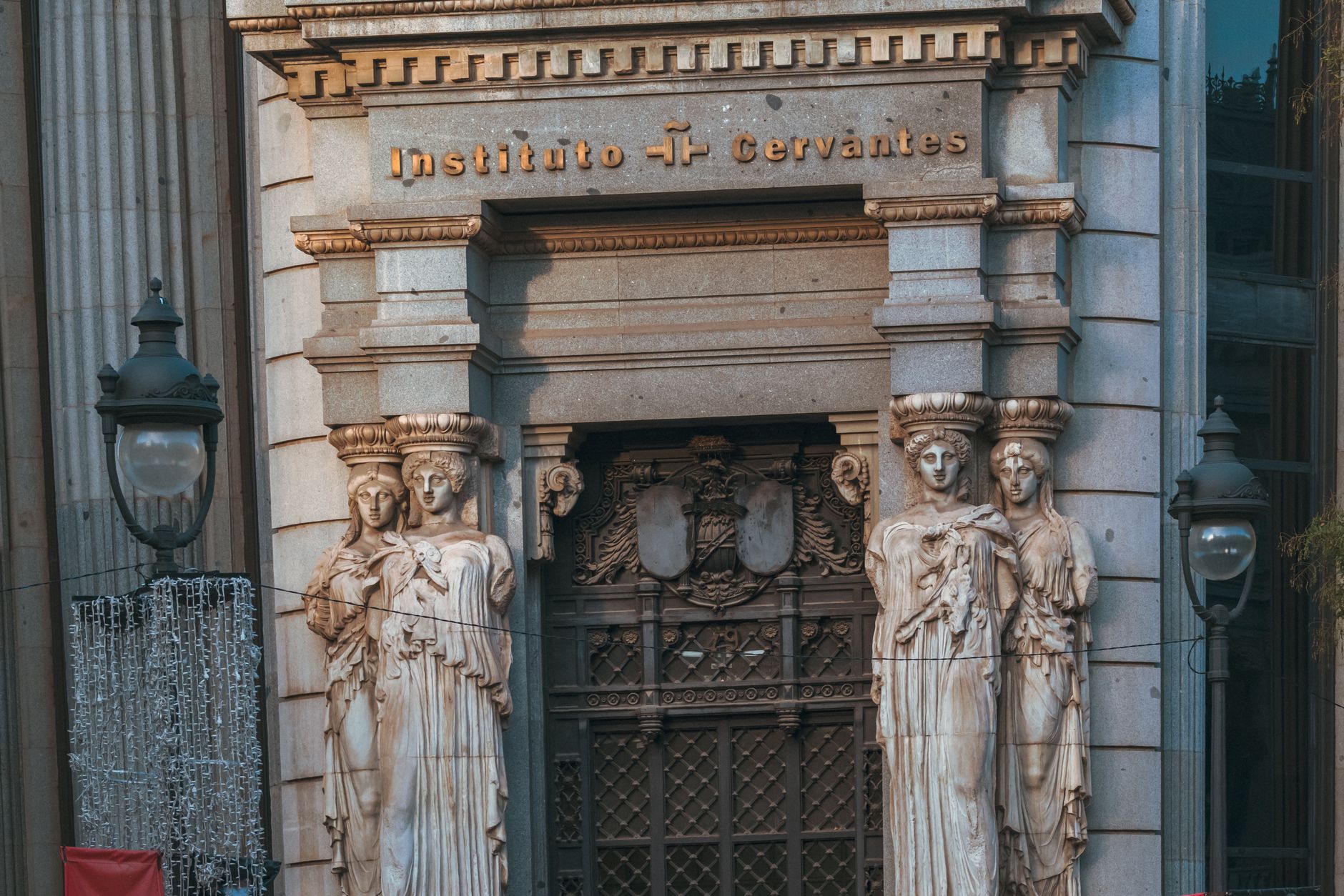 Front view of Instituto Cervantes entrance with classical sculptures in Madrid.