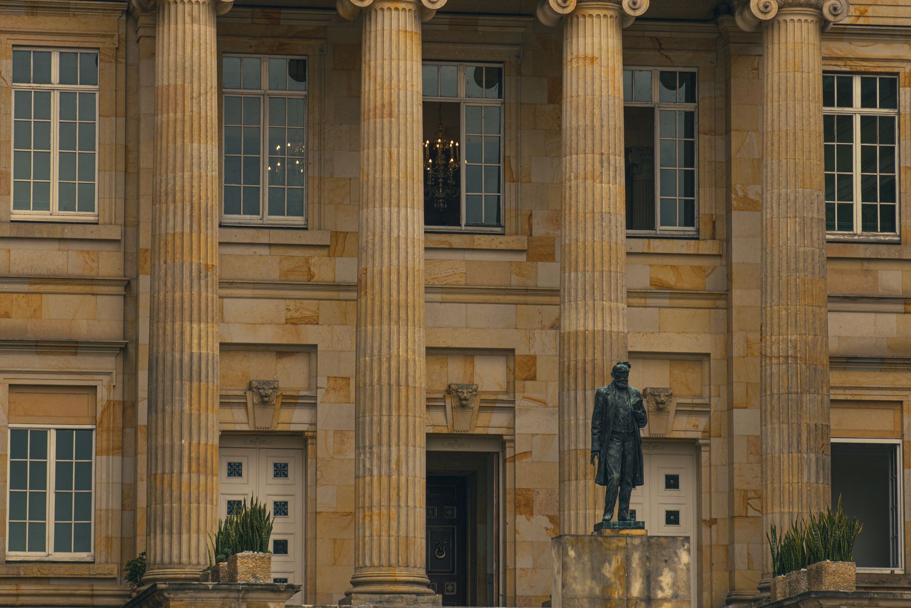 Elegant view of a classical building with pillars and a statue at the entrance.