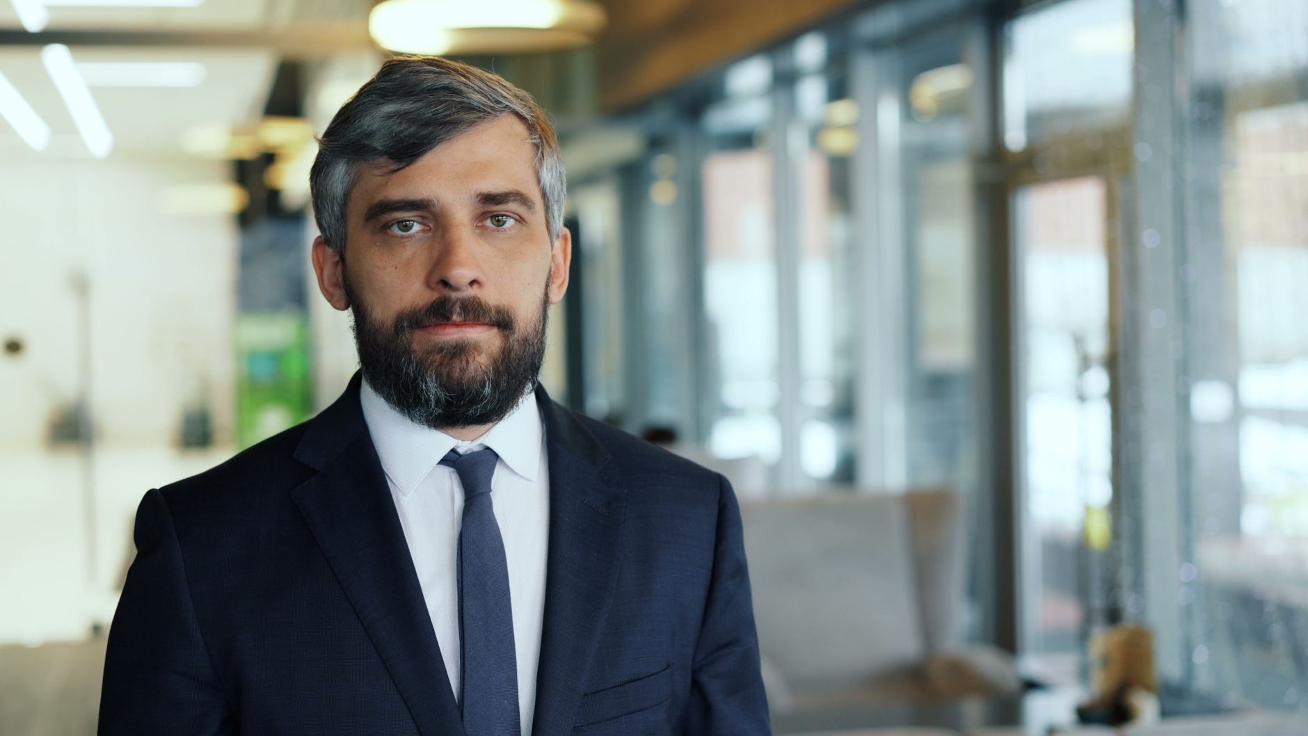 Professional businessman with a confident expression in a contemporary office environment.