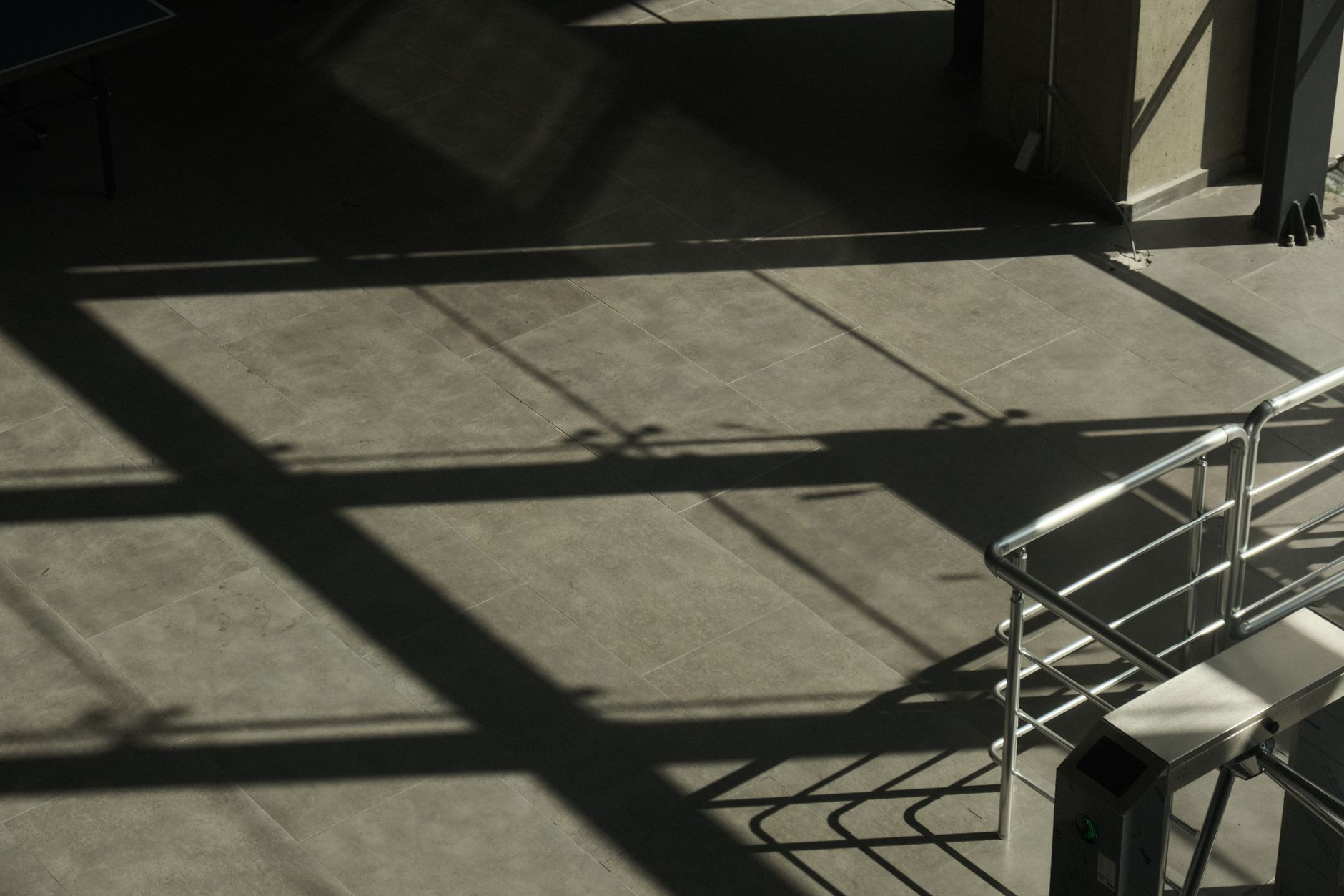 Concrete interior space with geometric shadows and metal handrails, creating a minimalist urban scene.