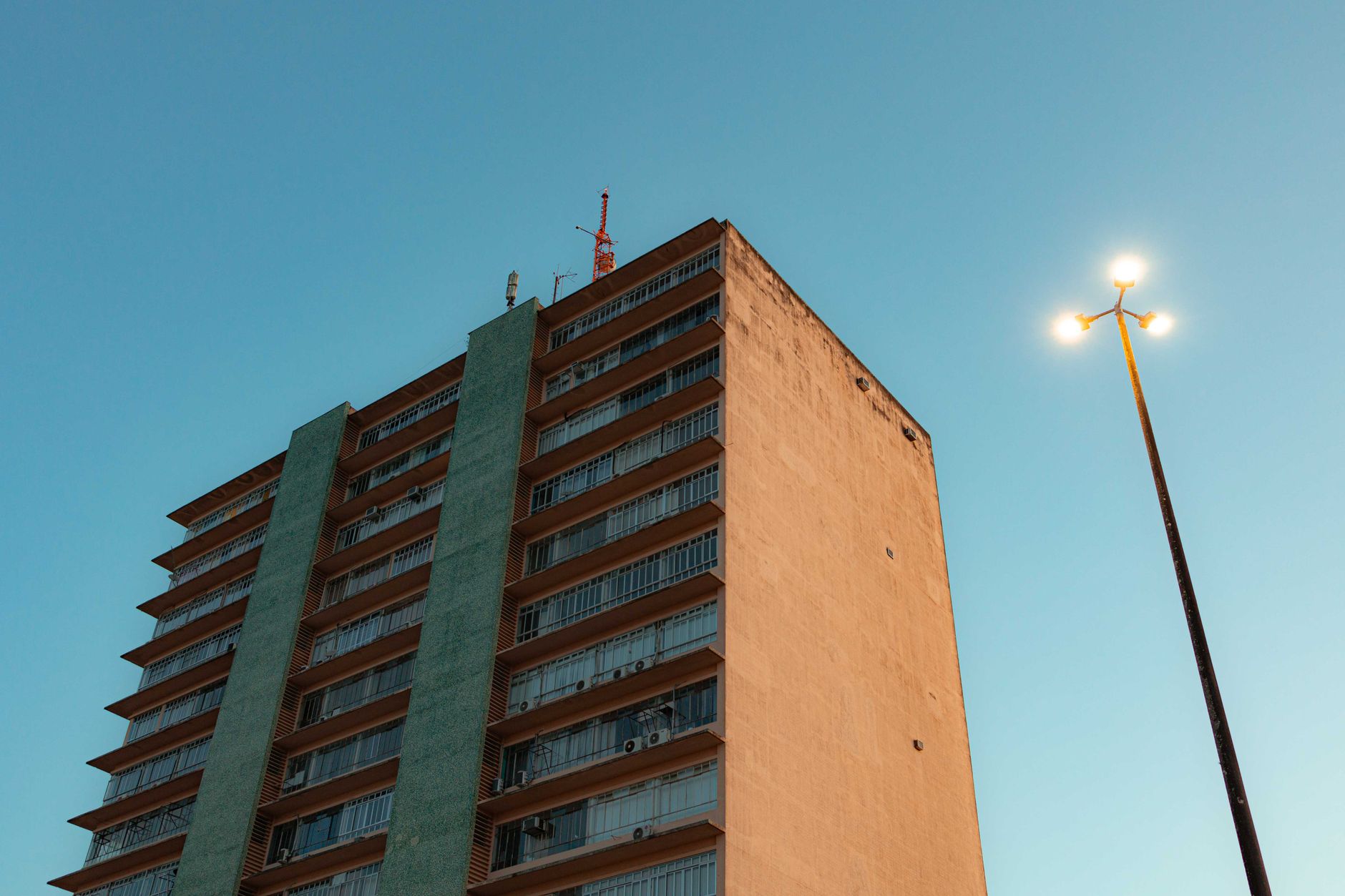 A city apartment block stands tall against a clear evening sky, under city lights.