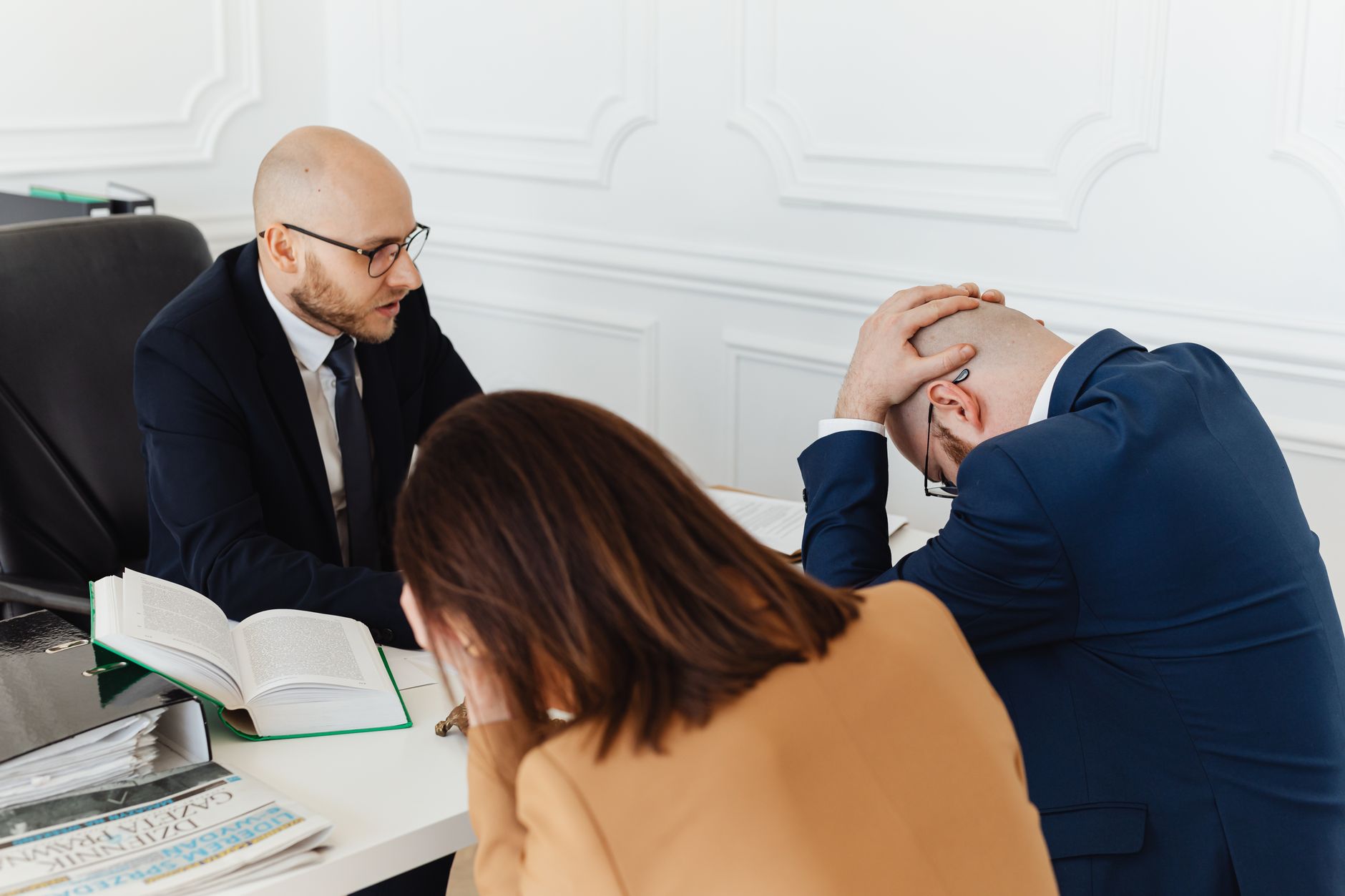 Legal professionals engaged in a tense meeting at a law office with open documents on the desk.