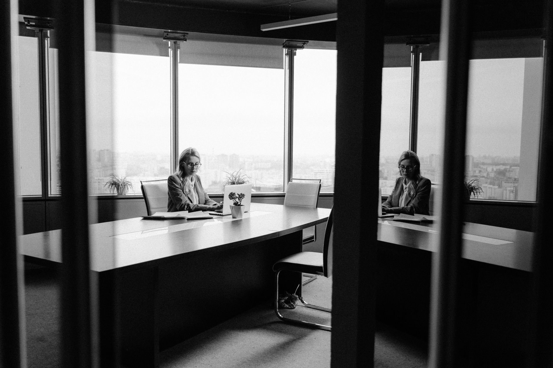 Caucasian woman in a modern office with a cityscape view, working with focus and poise.