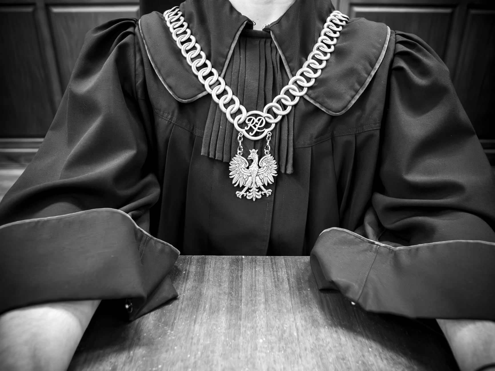 Monochrome photo of judge in traditional robes with emblematic necklace.