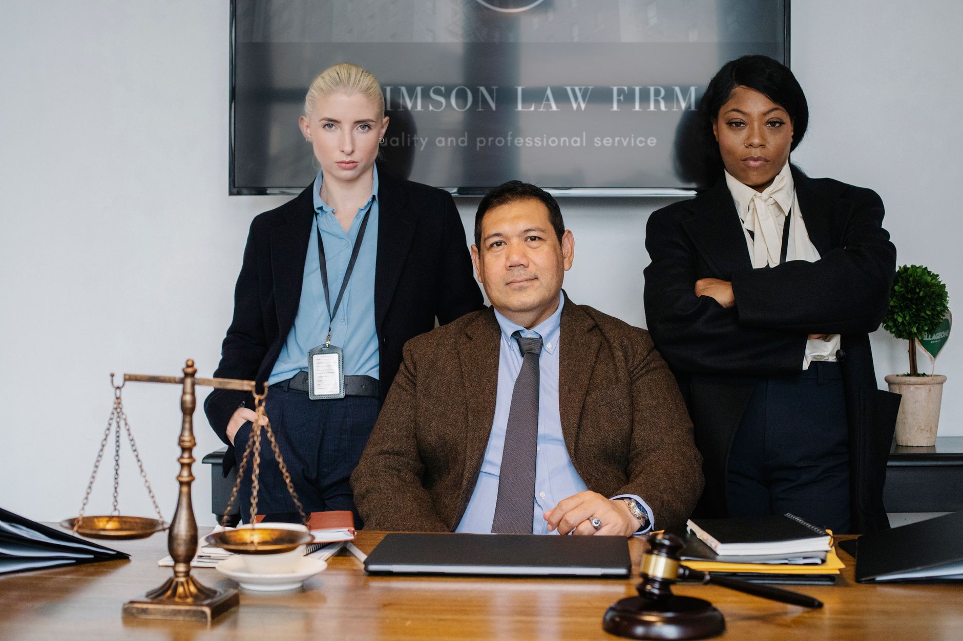 Group of successful multiethnic legislators looking at camera near table with scales of justice and folders