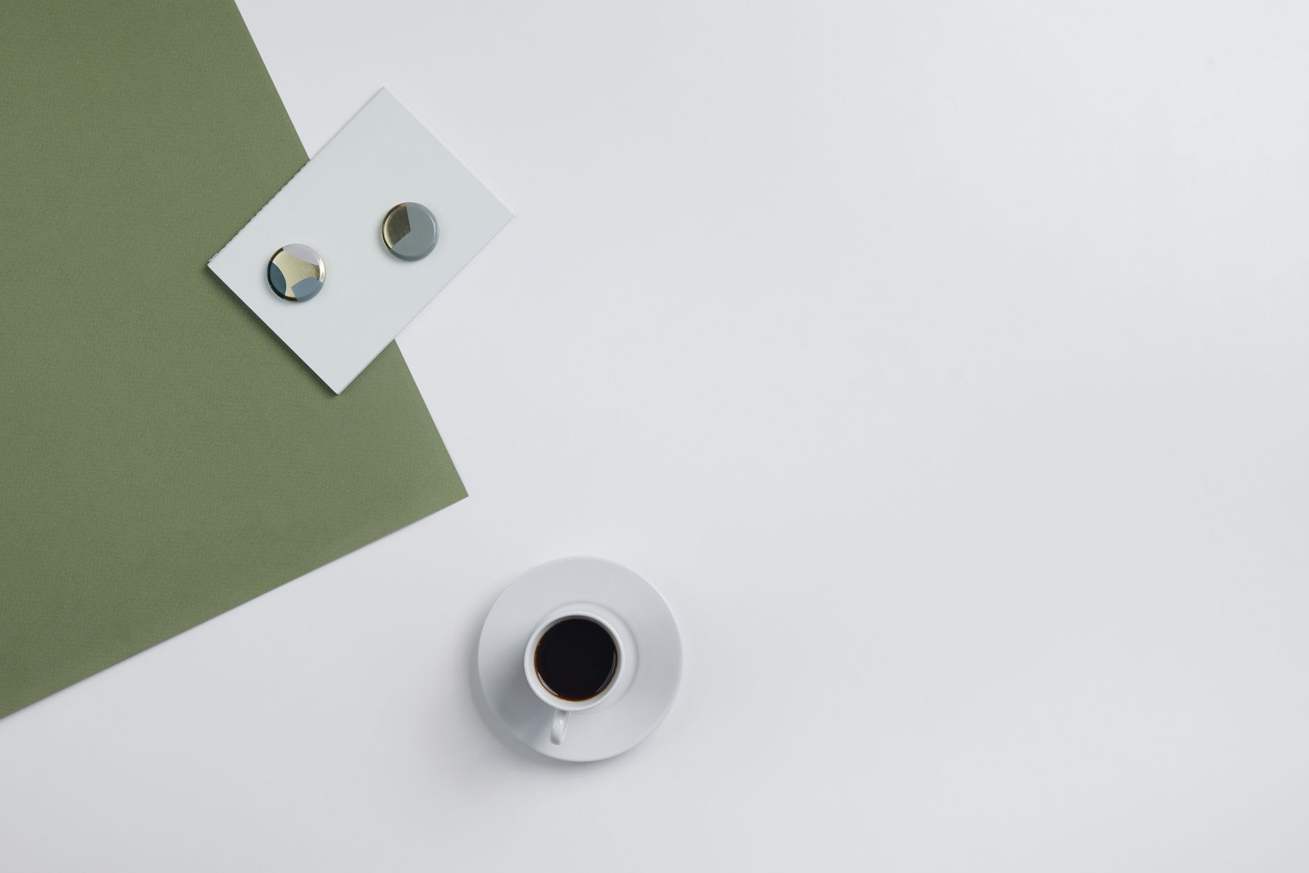 A minimalist flat lay featuring a coffee cup and geometric designs on a studio background.