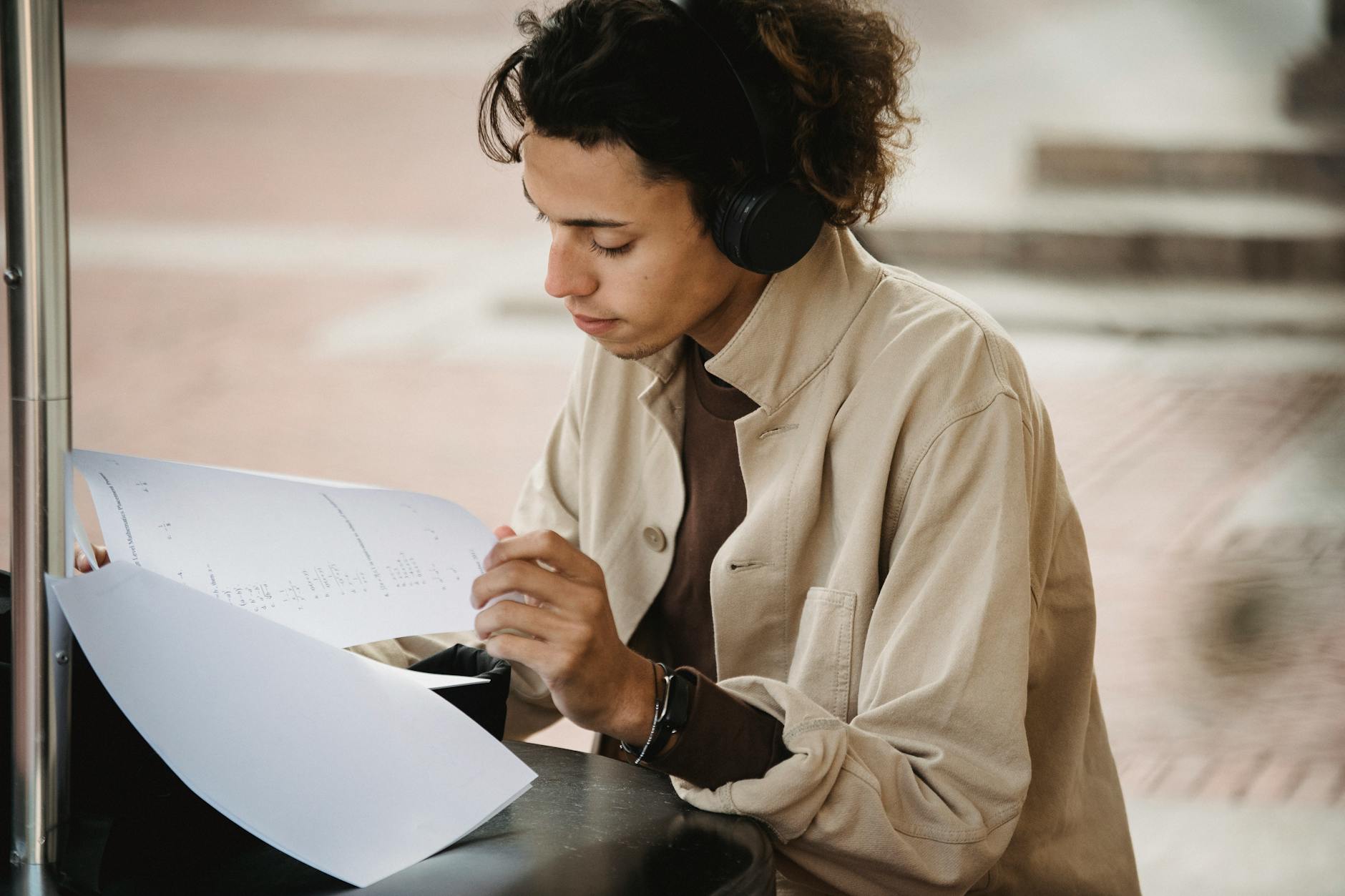 Crop focused learner doing task written on papers while using wireless headphones during studies