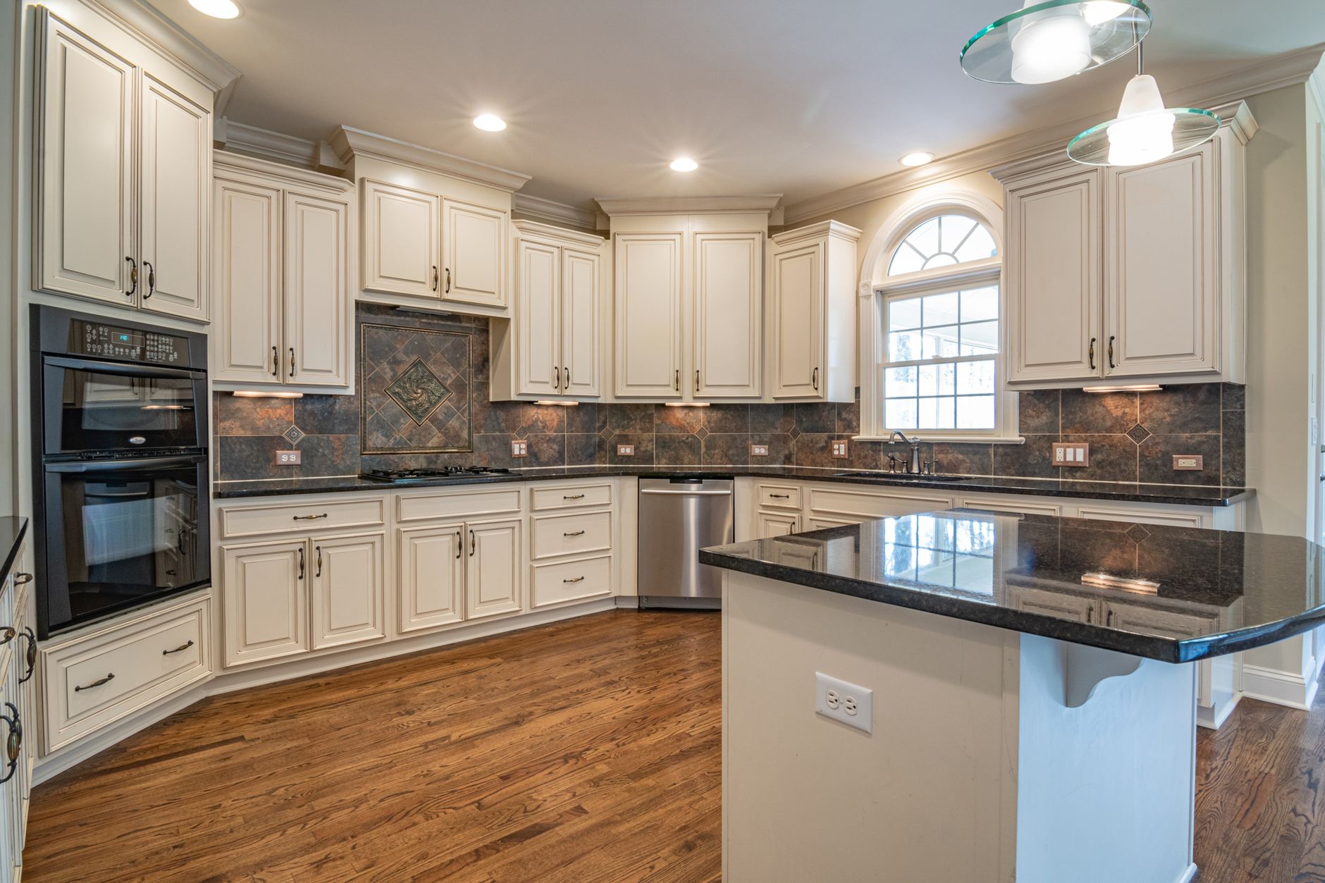 A spacious, modern kitchen with white cabinetry and a sleek black countertop, perfect for culinary enthusiasts.