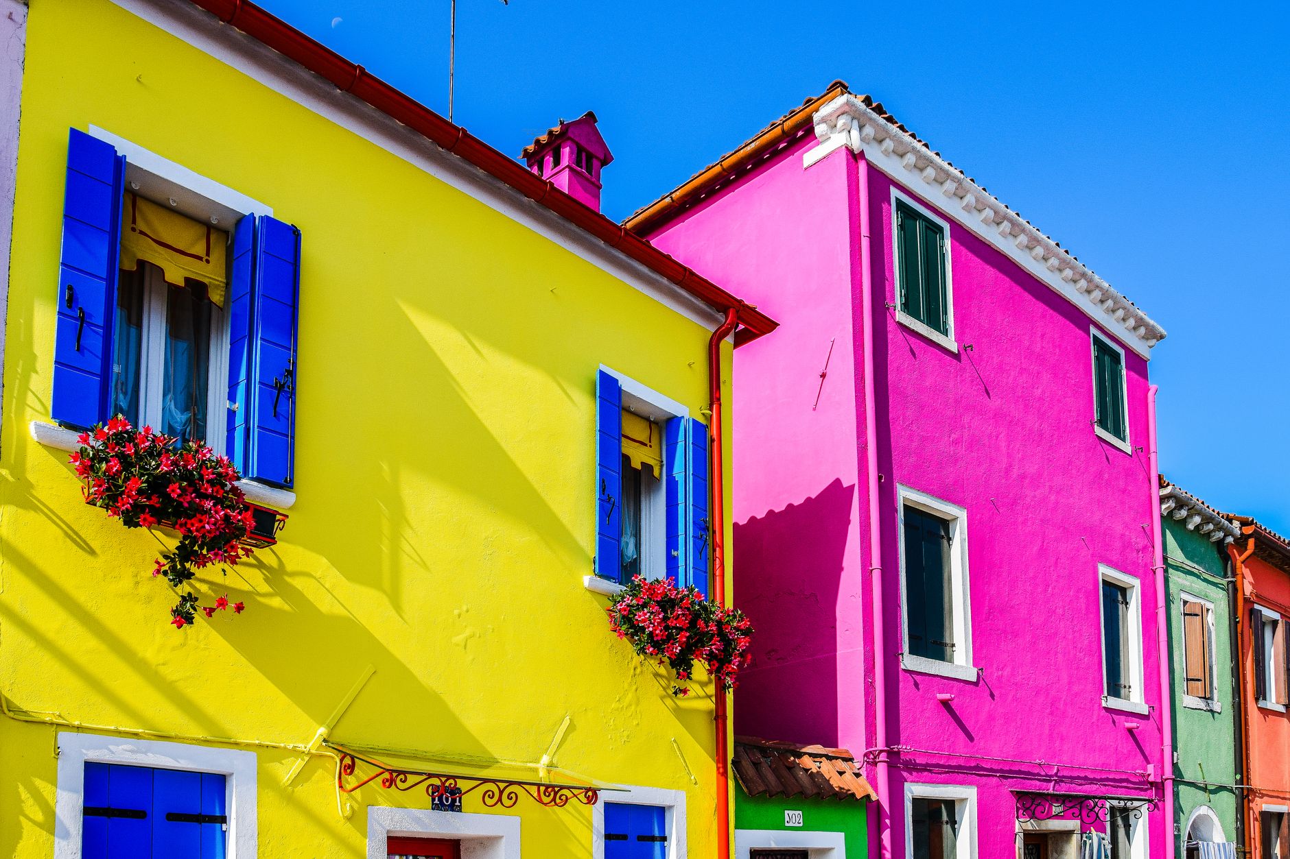 Brightly colored facades in the sunlit streets of Burano, Venice, Italy.