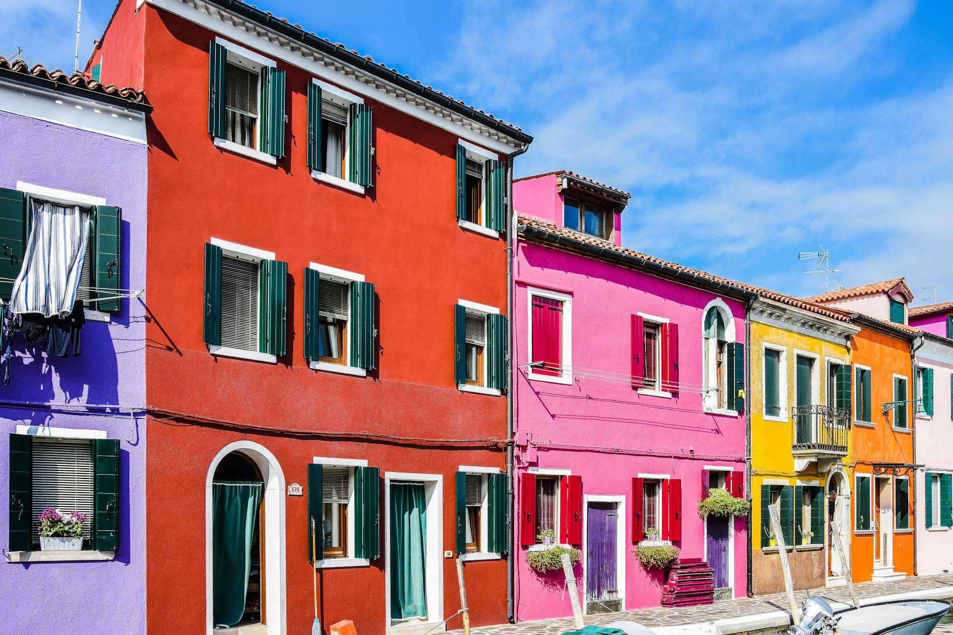 Vibrant multi-colored houses line the canal street in Burano, Venice.