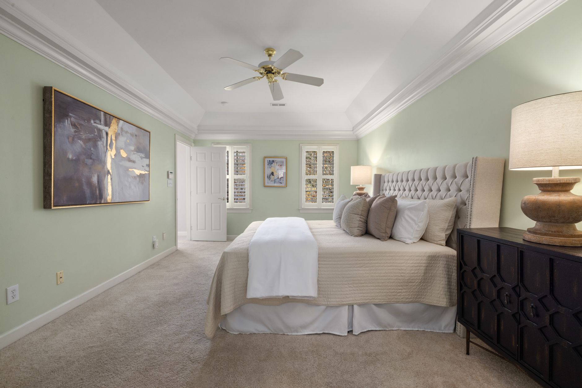 Elegant bedroom showcasing a king-sized bed, abstract art, and soft lighting for a cozy ambiance.