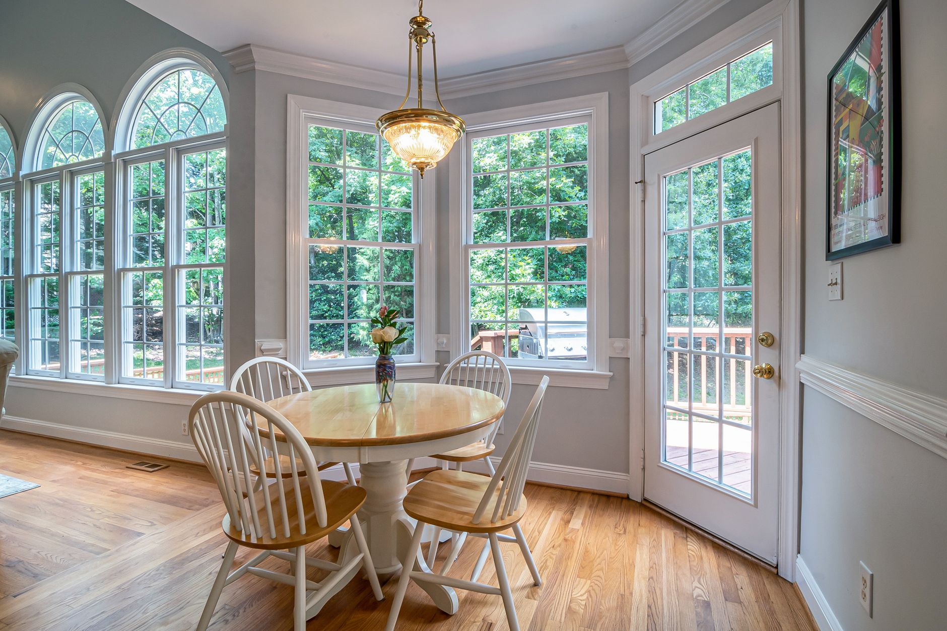 Bright and cozy dining area with round table and chairs, surrounded by glass windows.