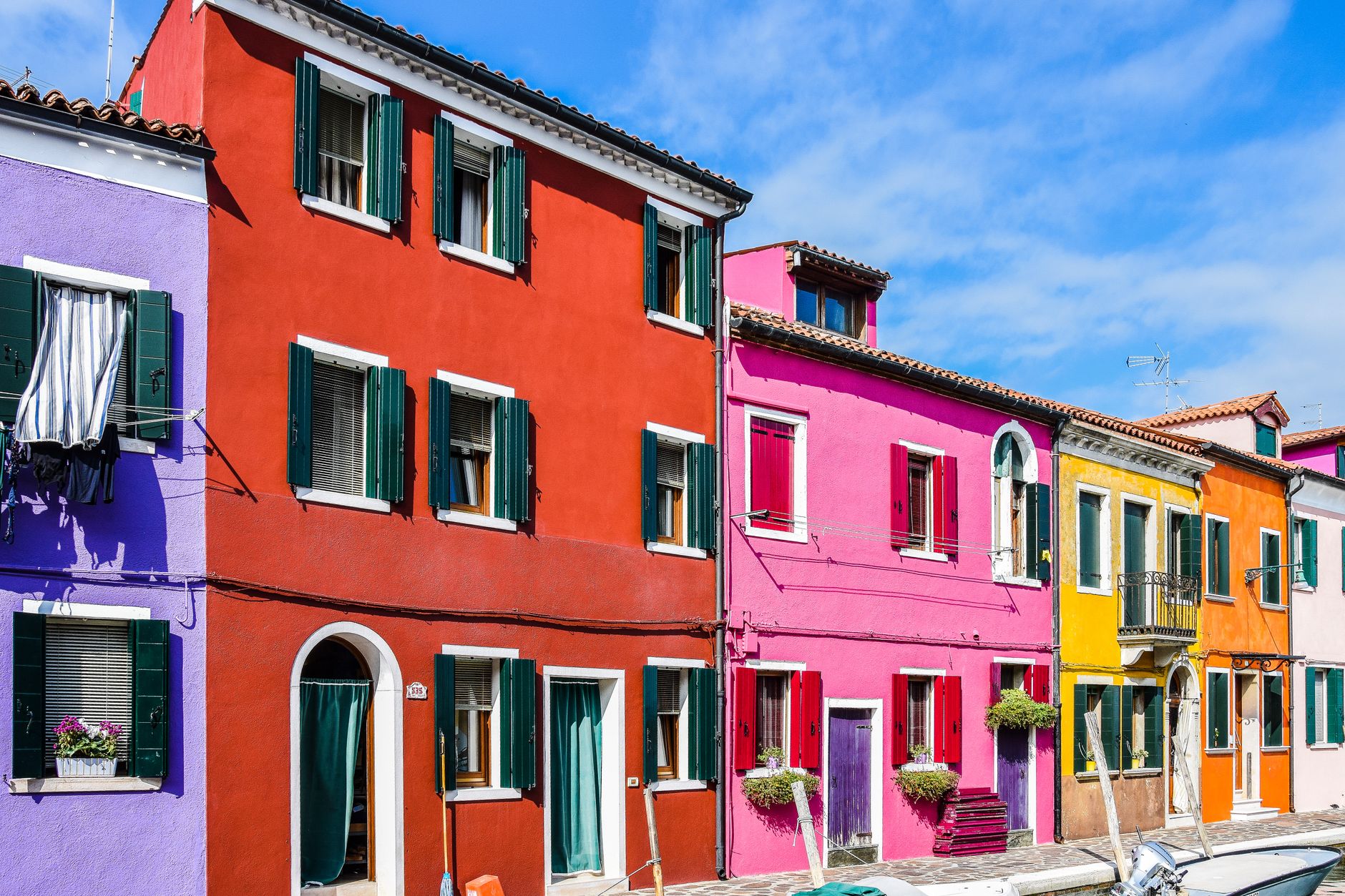 Vibrant multi-colored houses line the canal street in Burano, Venice.