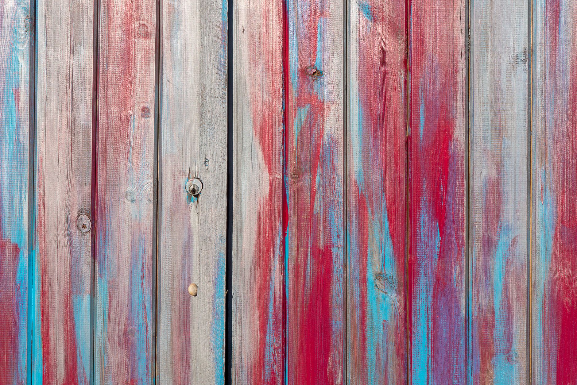 Close-up of a colorful wooden fence with artistic red and blue paint strokes.