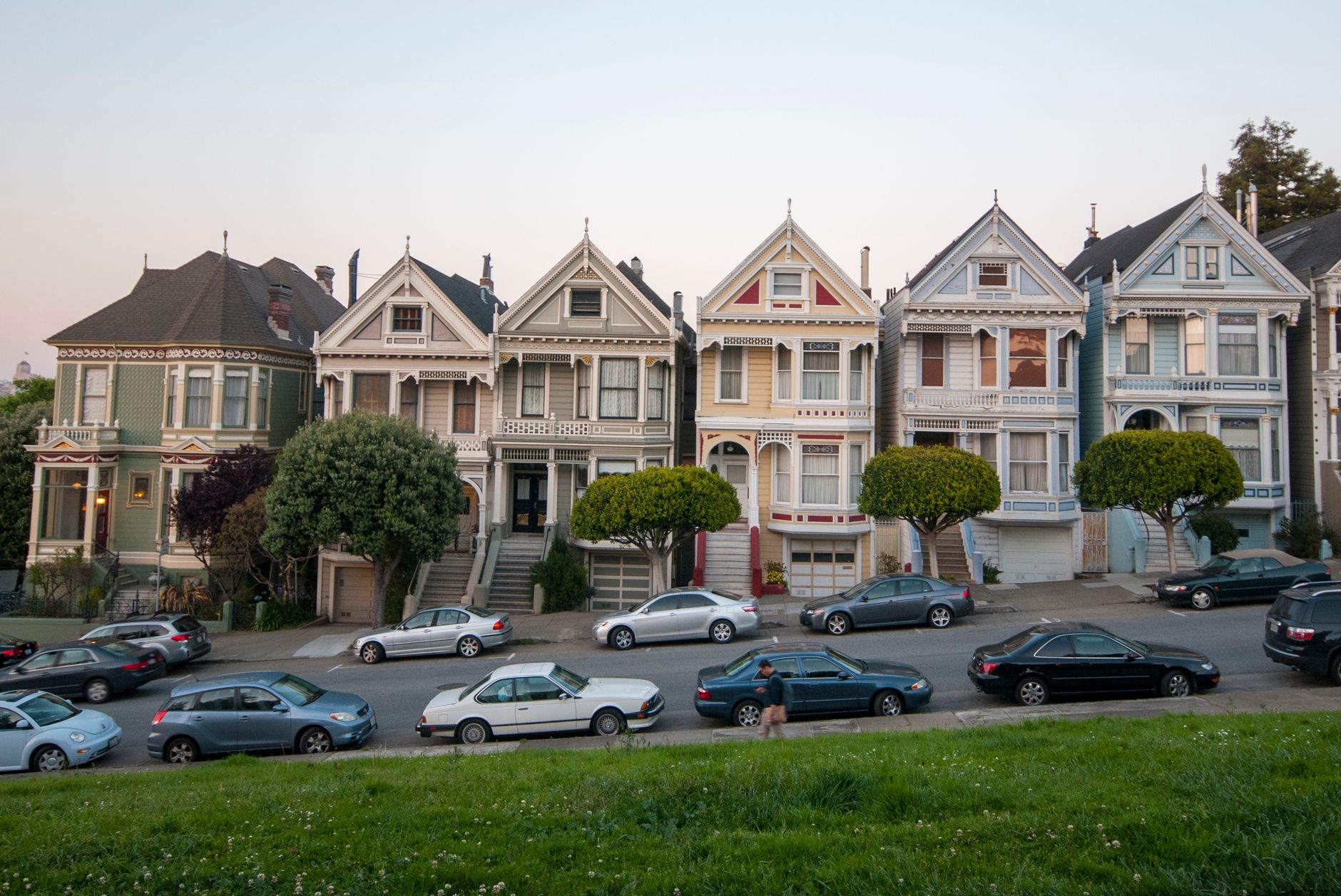 Classic Victorian houses known as Painted Ladies against a San Francisco backdrop at dusk.