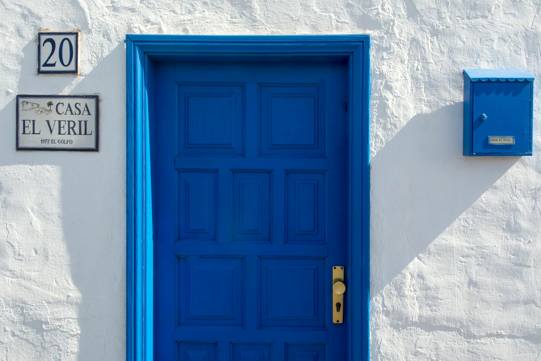 Vibrant blue door with mailbox and street sign, offering a striking facade.