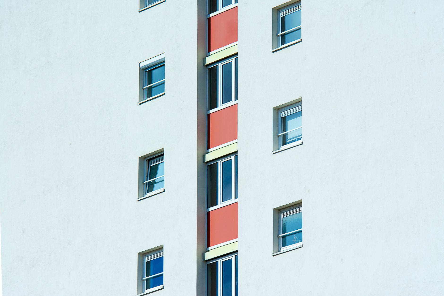 Close-up view of a modern multi-storey apartment building exterior with symmetrical windows and colorful design.