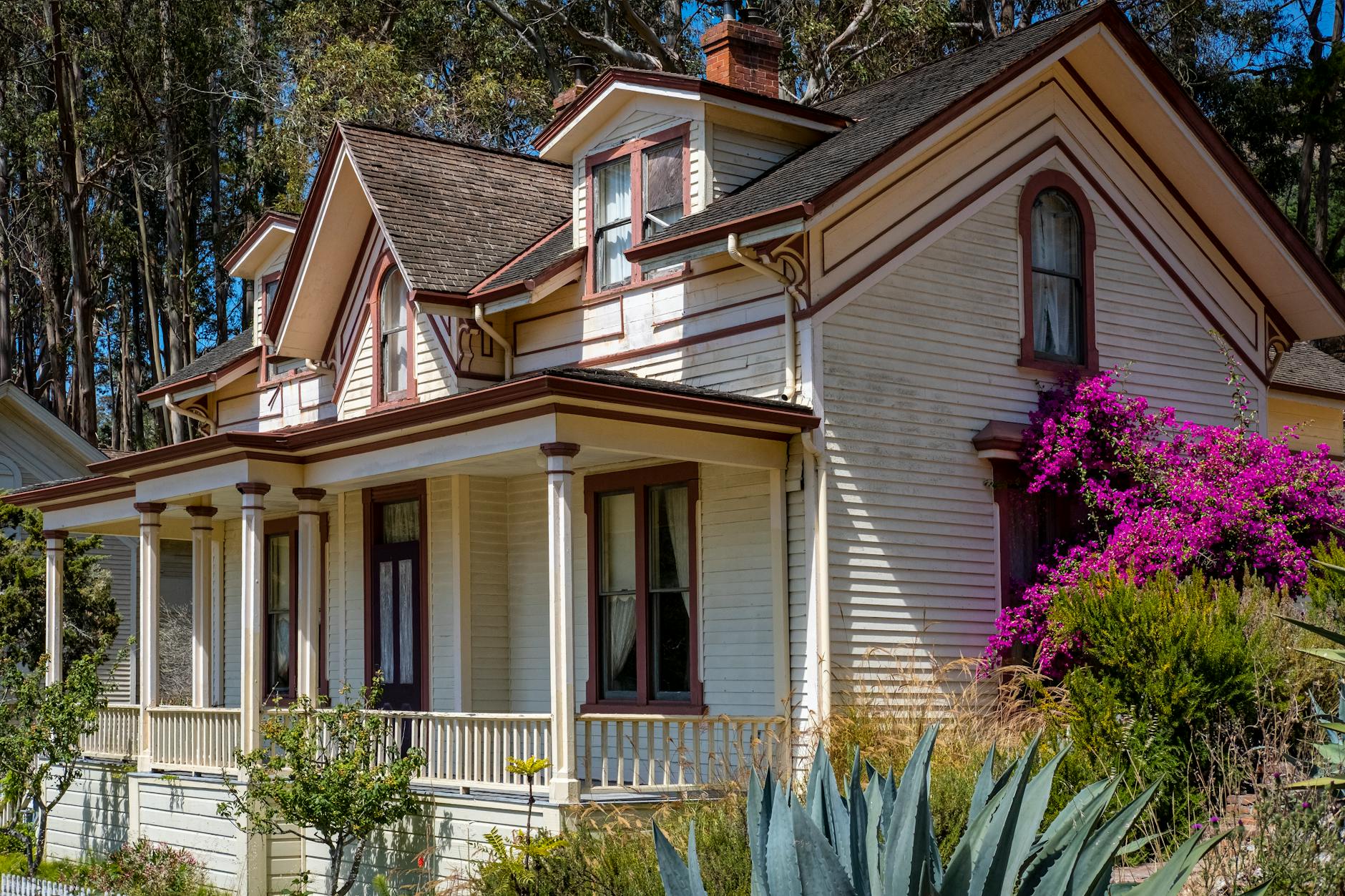 Beautiful Victorian house surrounded by vibrant gardens and trees, perfect for architecture and nature lovers.