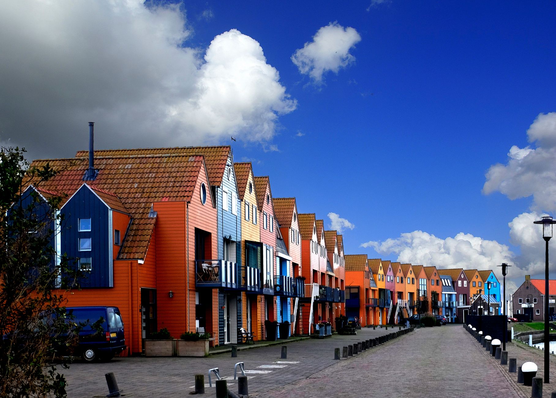 Vibrant row houses under a bright blue sky in Stavoren, highlighting Dutch urban architecture.