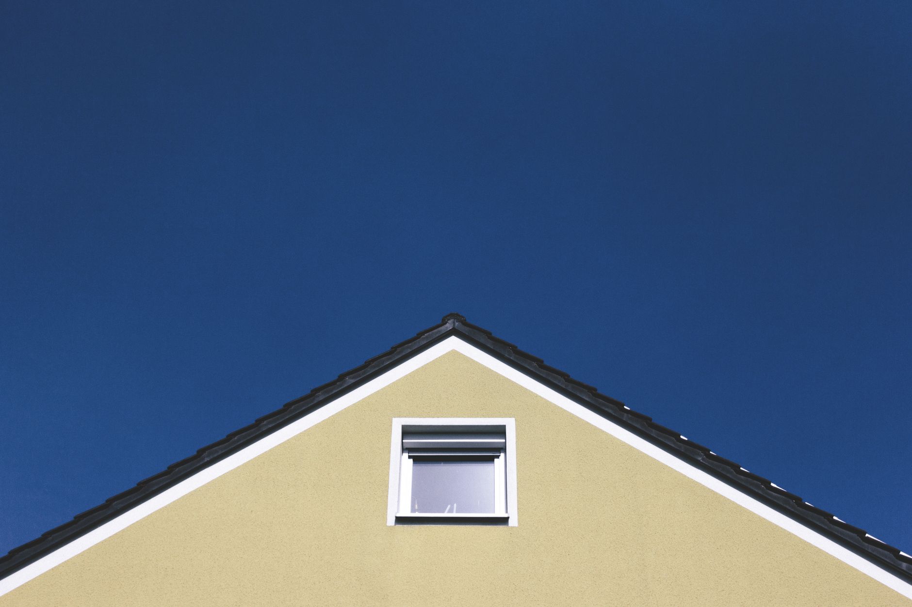 A modern house gable against a clear blue sky, highlighting minimalistic architectural design.