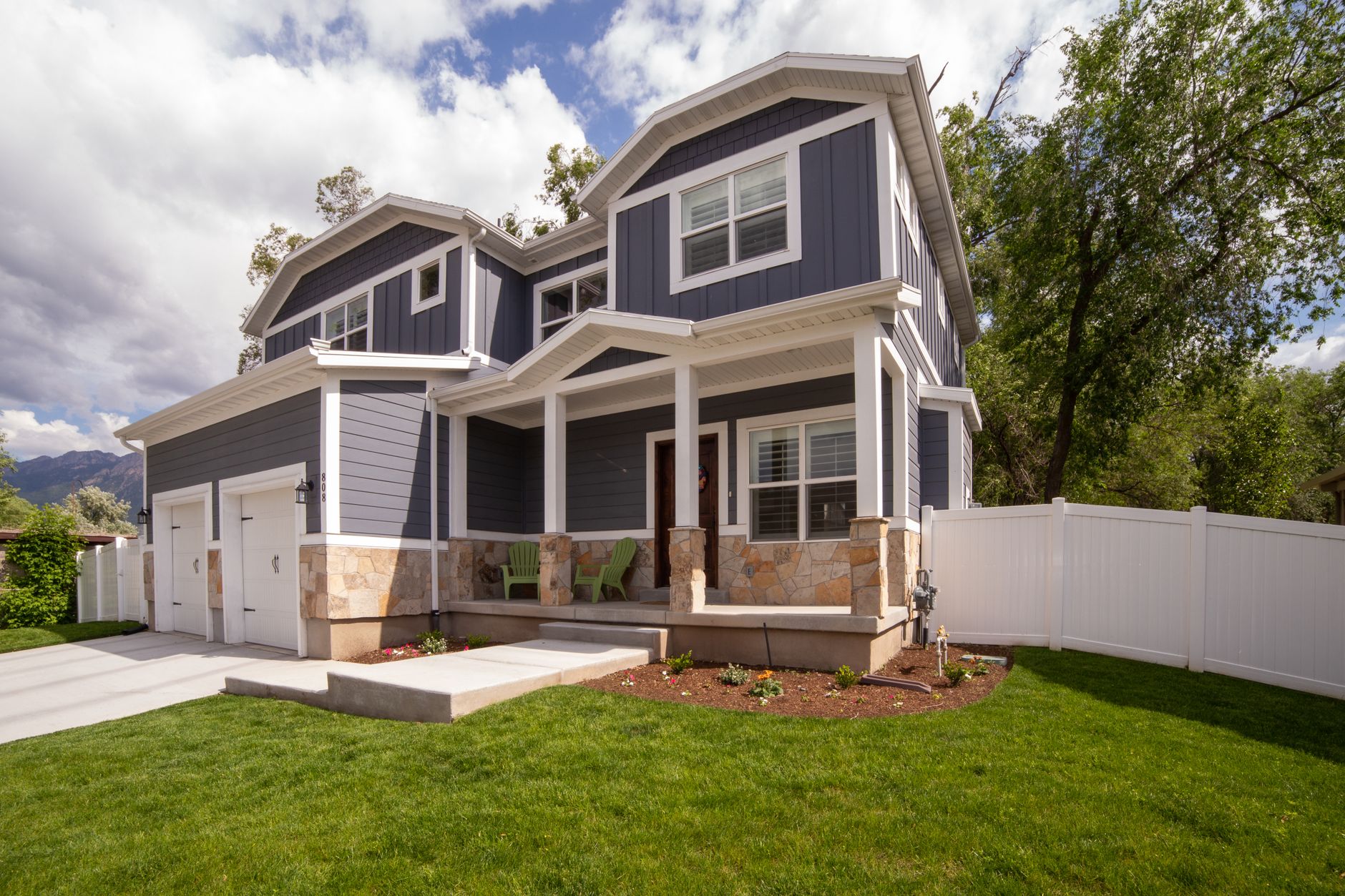 A modern two-story house with front porch and attached garage in a suburban setting.