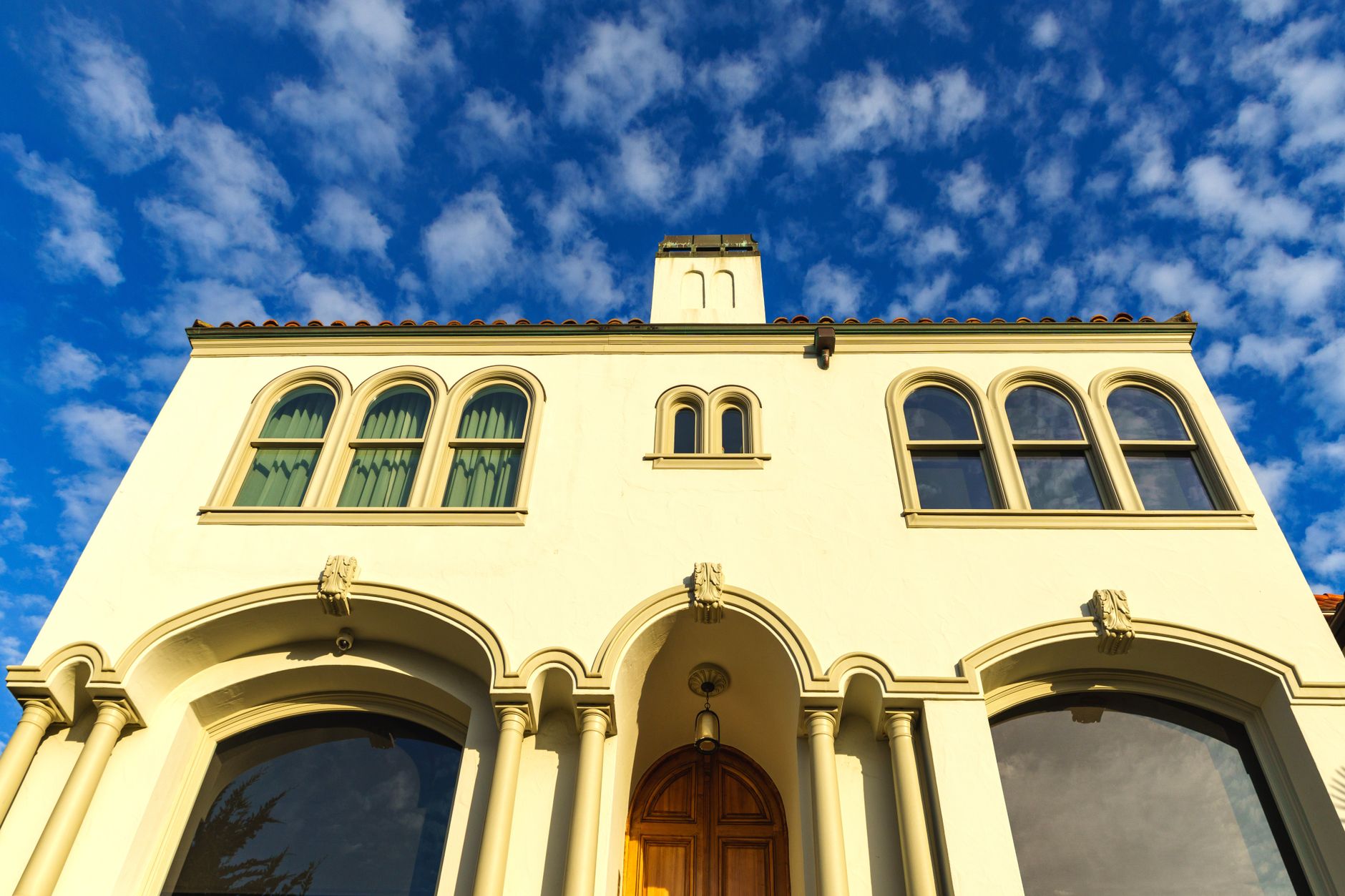Stunning Mediterranean-style building facade with arched windows against a bright blue sky.
