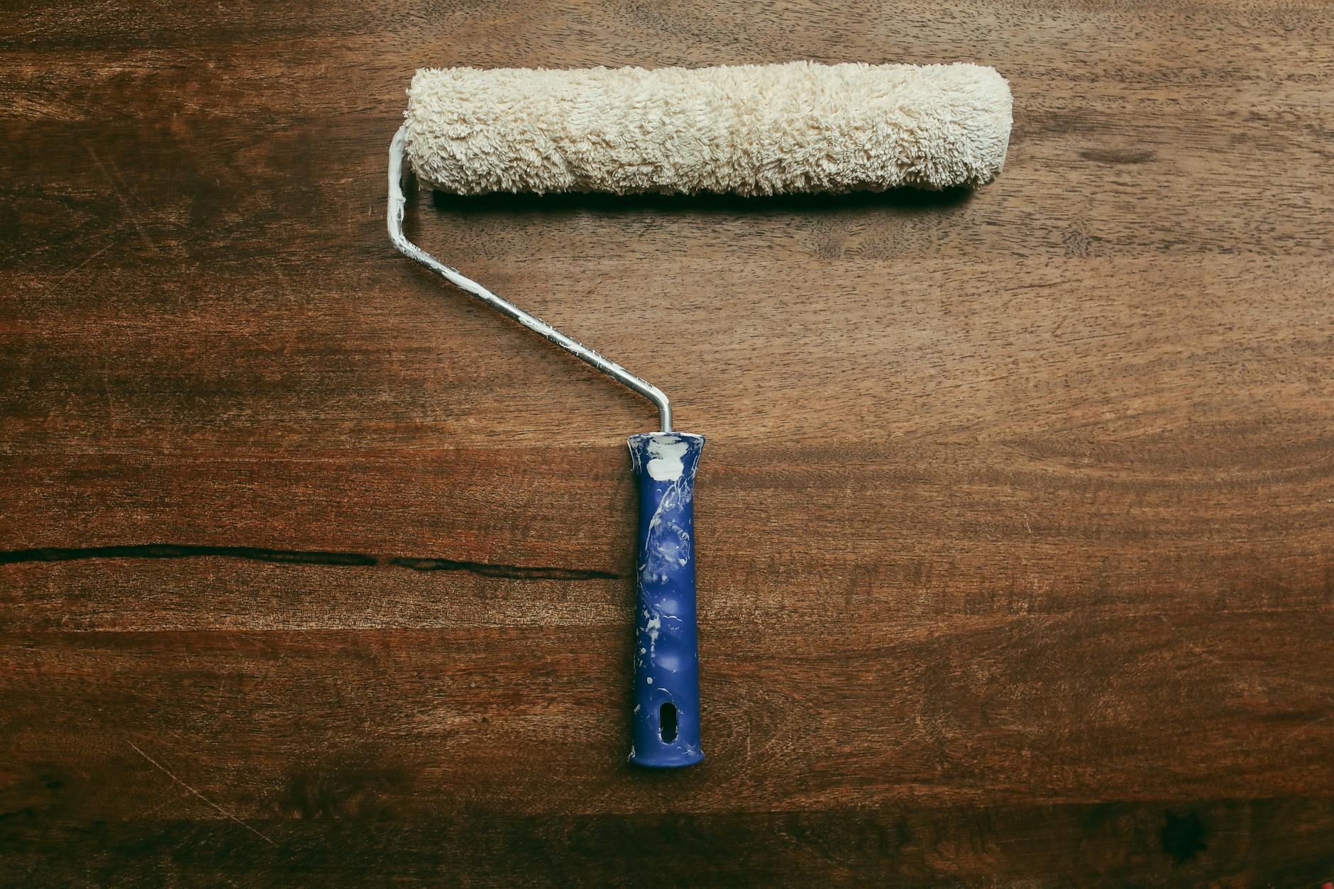 A worn paint roller placed on a wooden surface, ideal for DIY home improvement visuals.