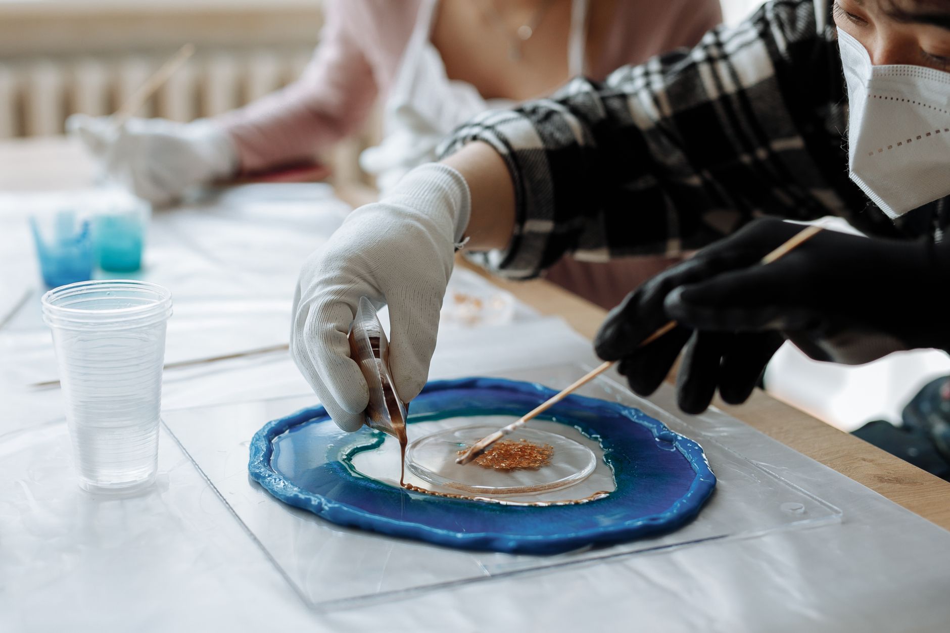Close-up of artists using resin and pigments for creating unique artwork.