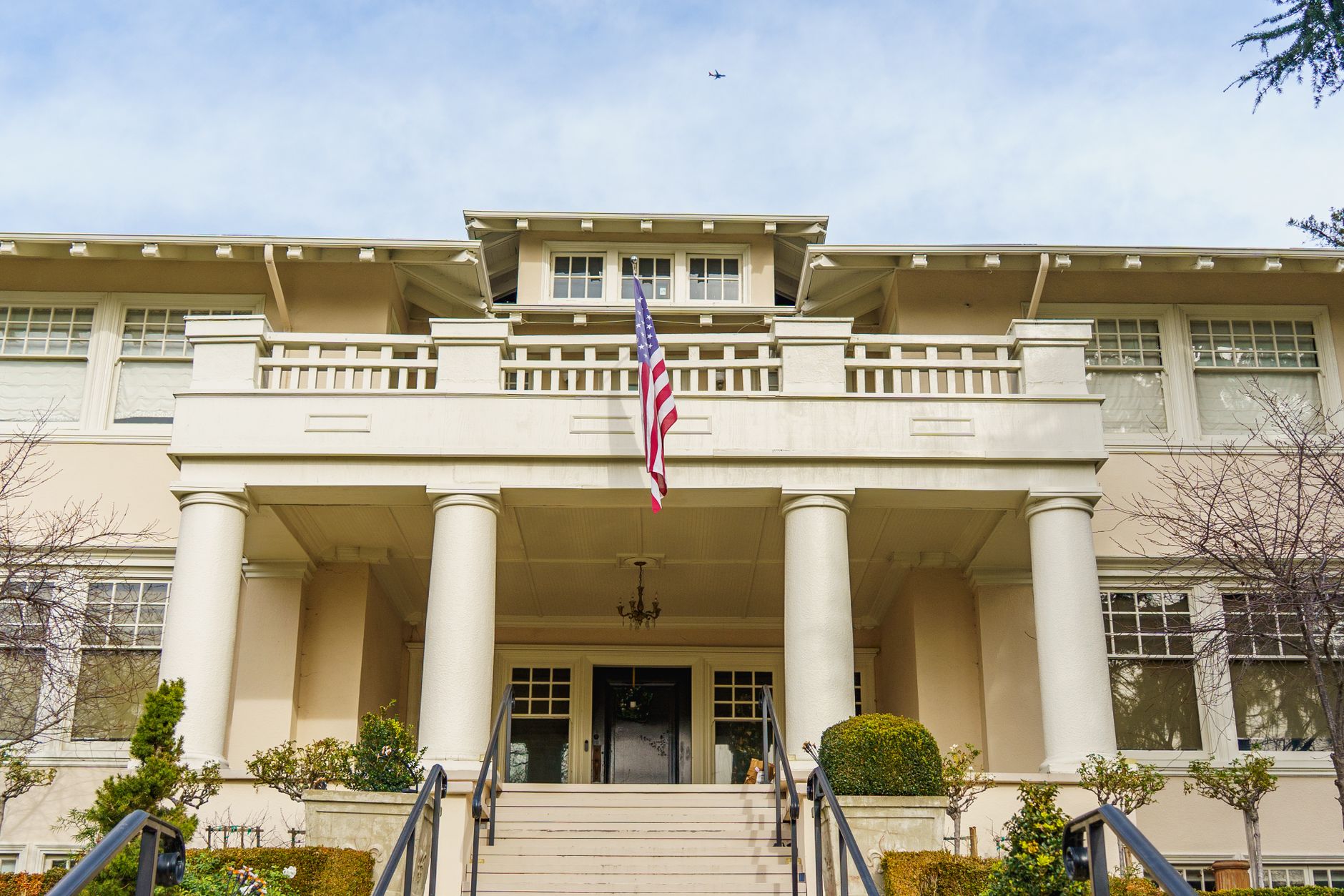 Stately colonial-style house with columns and an American flag, exuding historic charm.