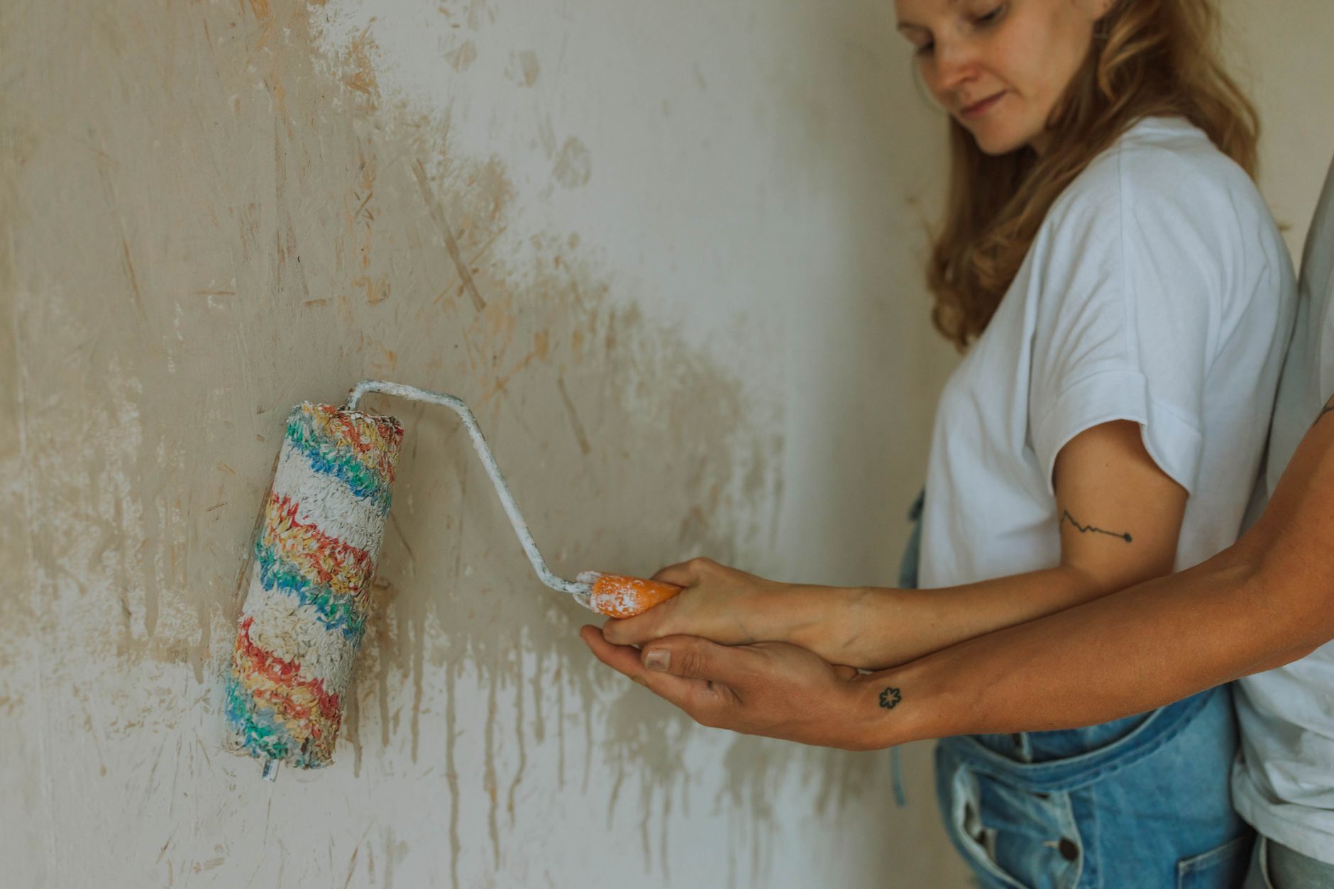 A couple working together to paint a wall, capturing a moment of home renovation and teamwork.