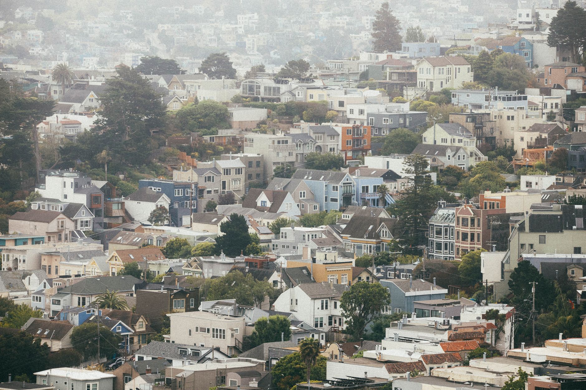 Scenic view of the foggy San Francisco hills with colorful houses under a cloudy sky.