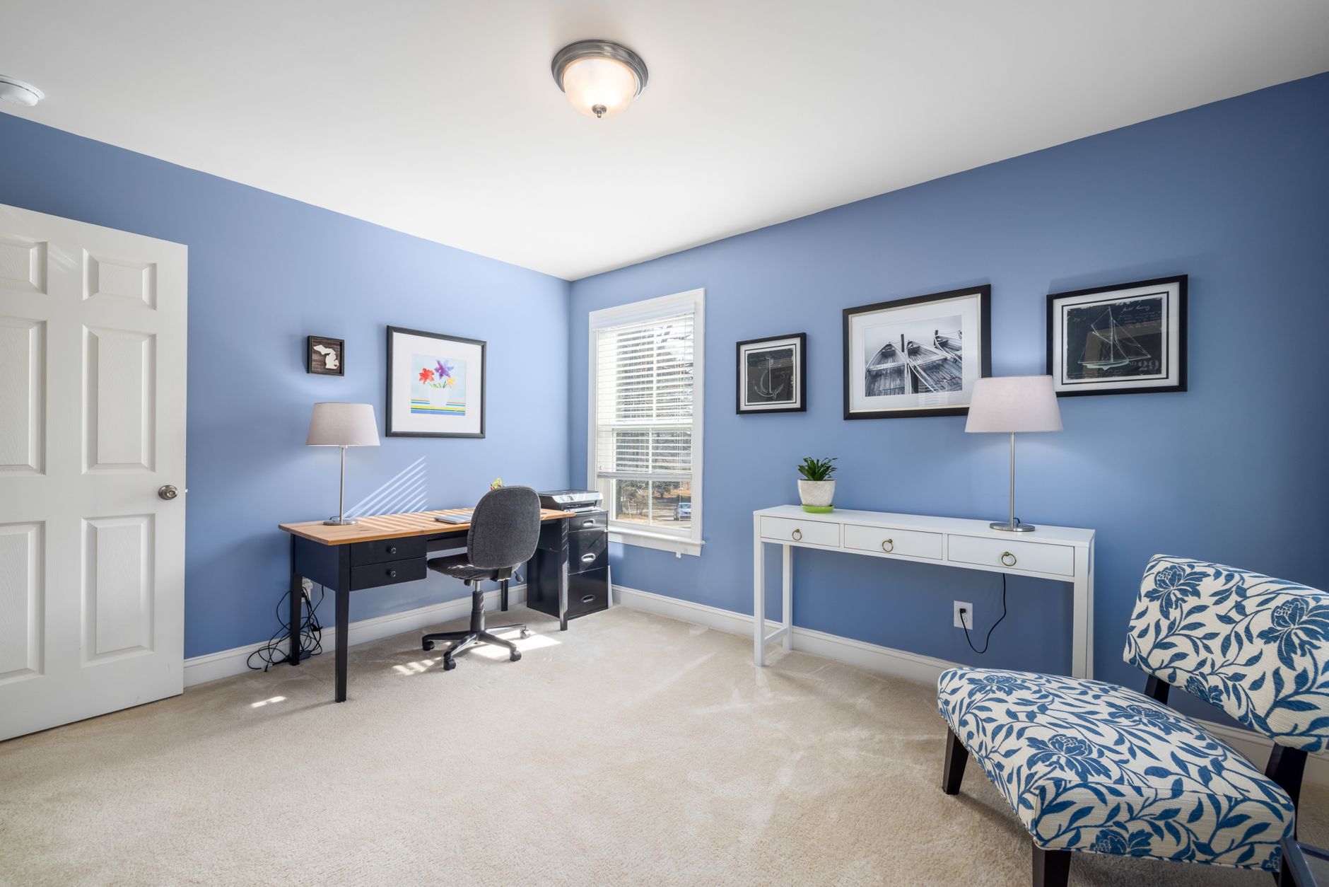 A stylish home office with blue walls, featuring a desk, chair, and laptop, ideal for productivity.